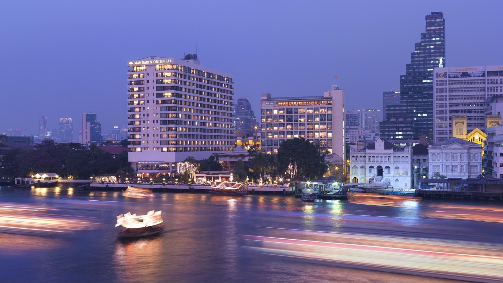 Mandarin Oriental, Bangkok on the Chao Phraya at dusk, with boats on the river and towers behind