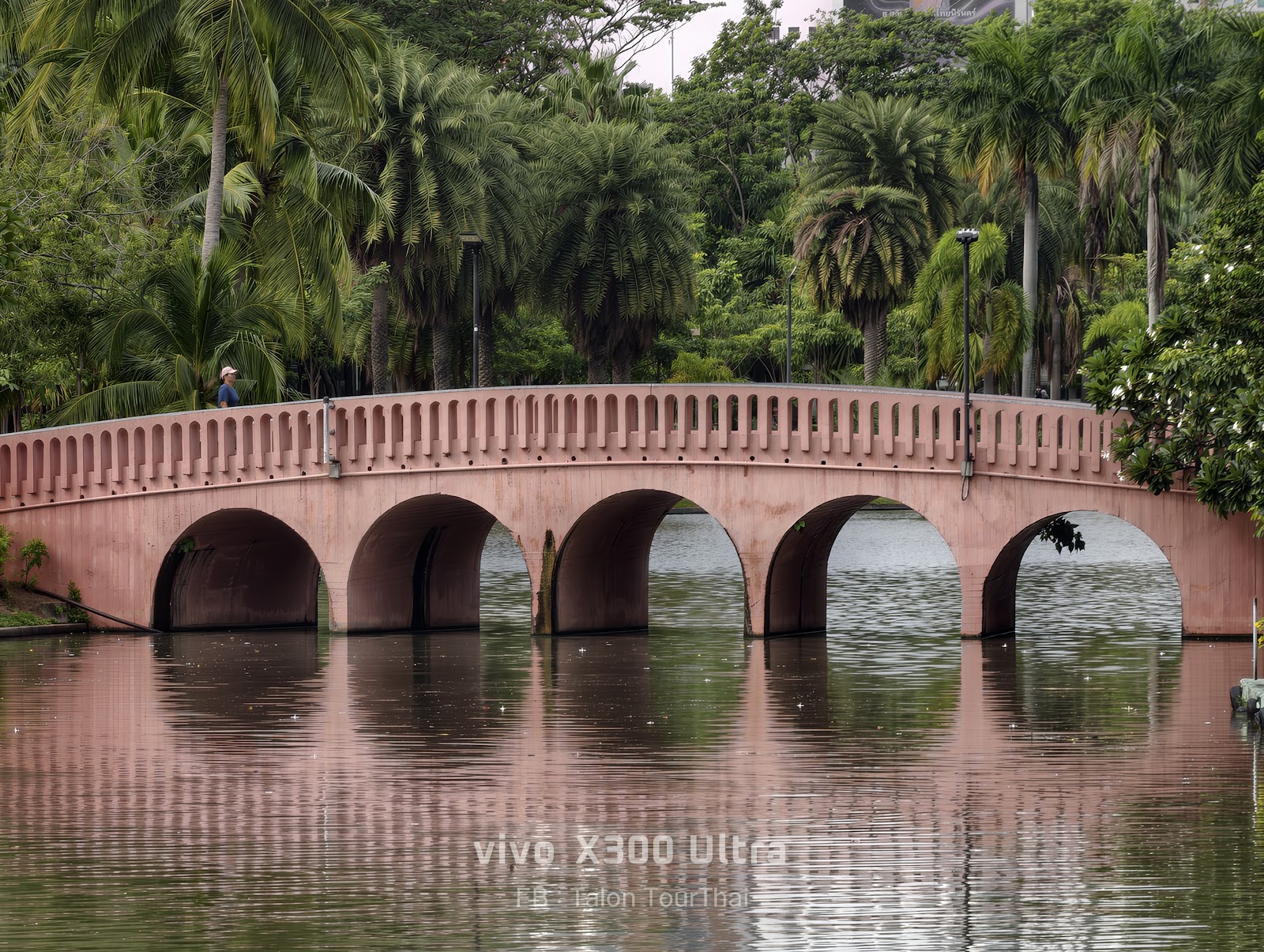 A brick arched bridge reflected in the lake at Chatuchak Park
