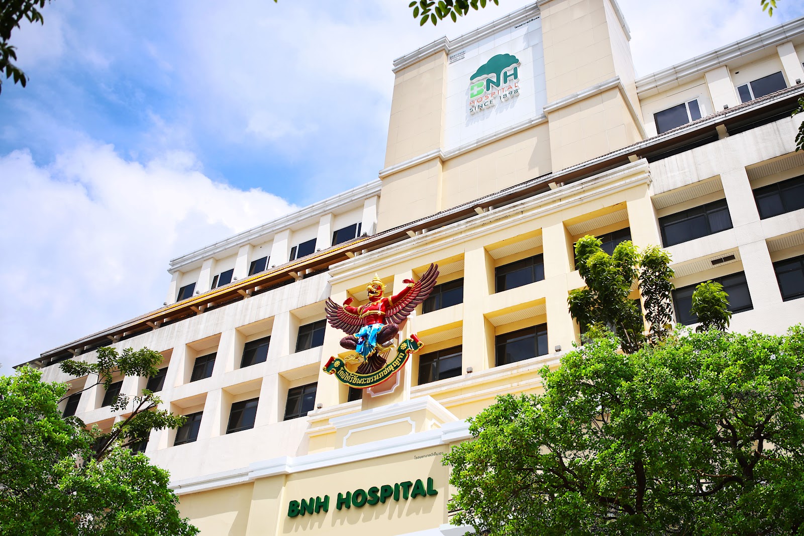 The cream facade of BNH Hospital with its name and green roof emblem