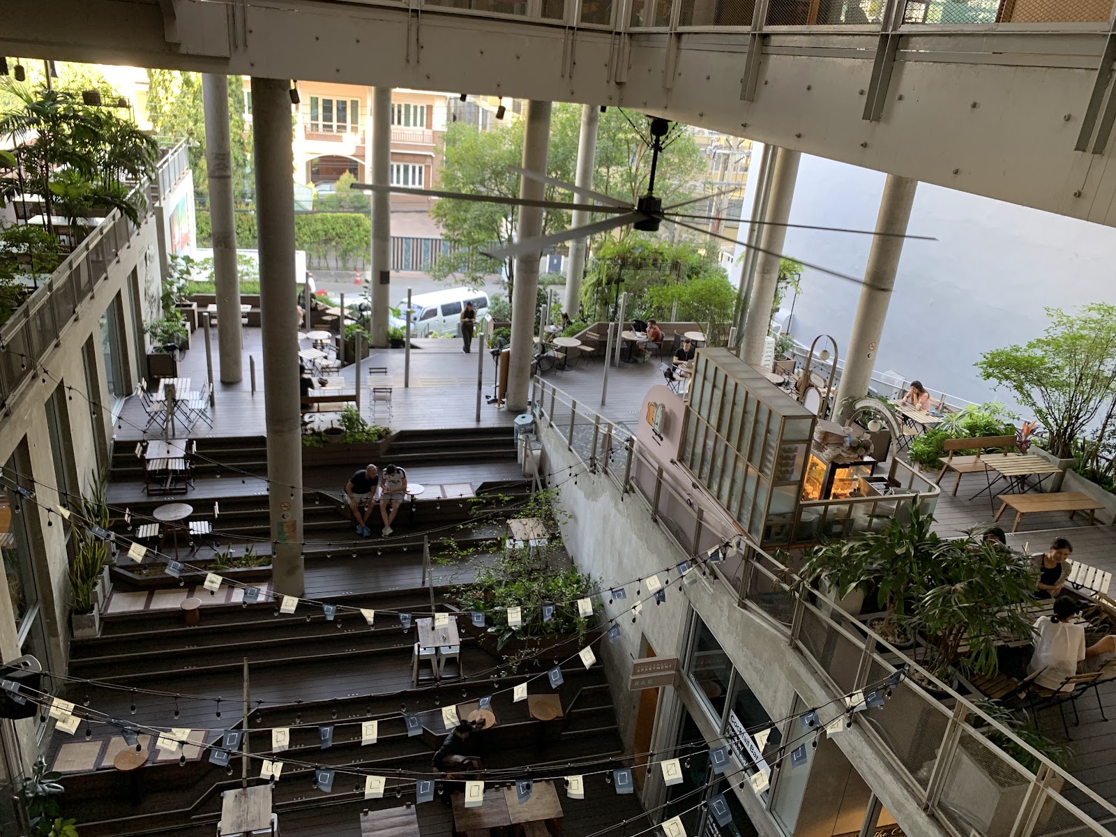 The open, multi-level interior of theCOMMONS Thonglor with seating and greenery