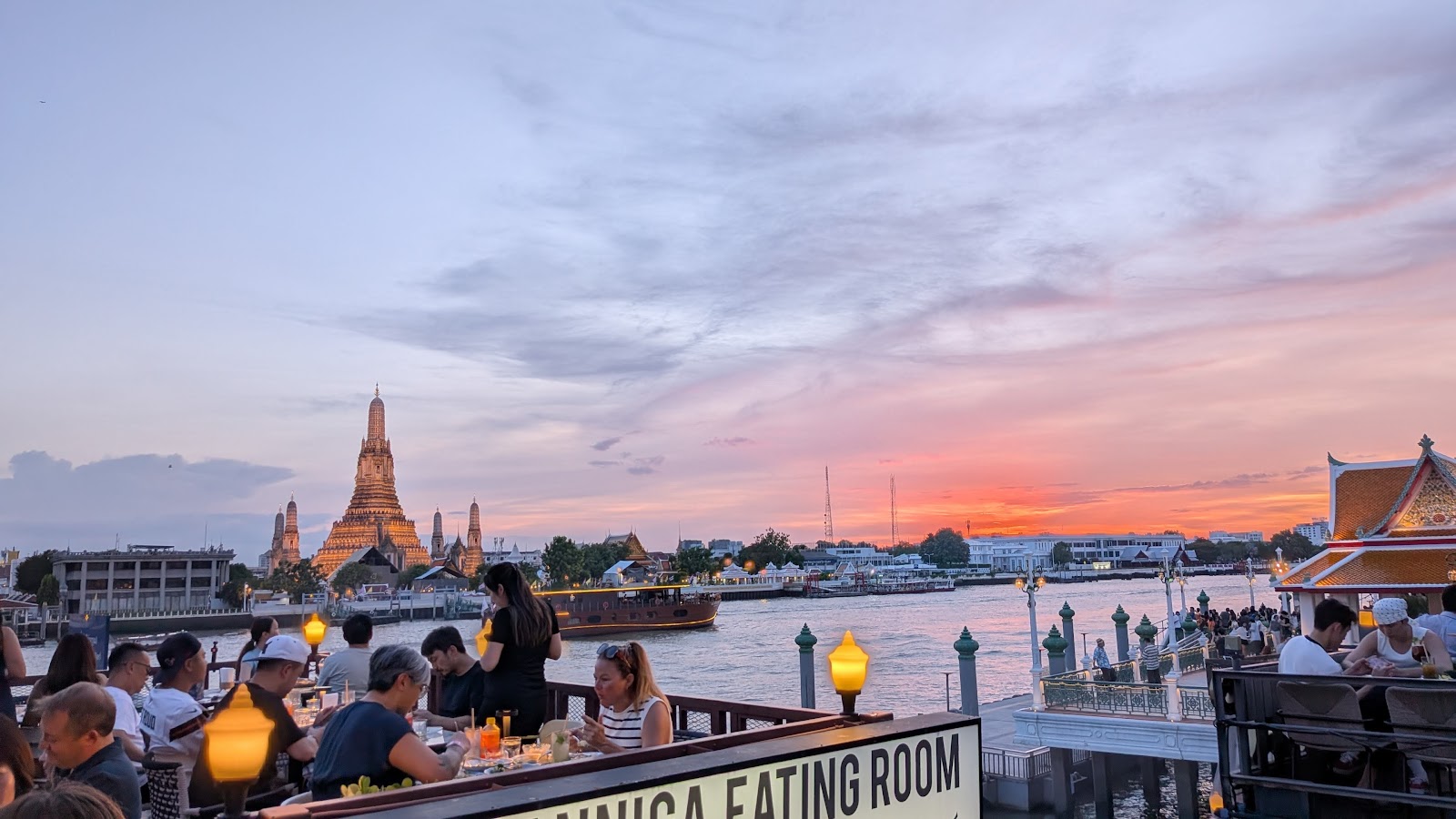 Wat Arun across the Chao Phraya at sunset, seen from the riverside terrace of Supanniga Eating Room