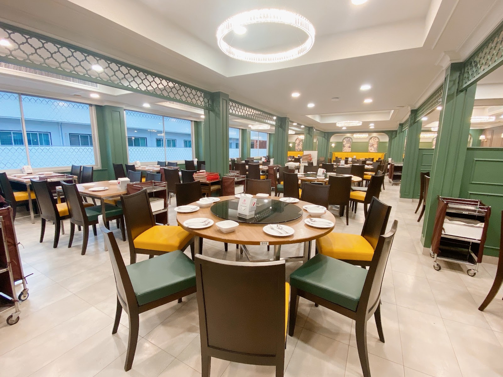 Dining room at Somboon Seafood with round tables, green chairs and a lazy Susan