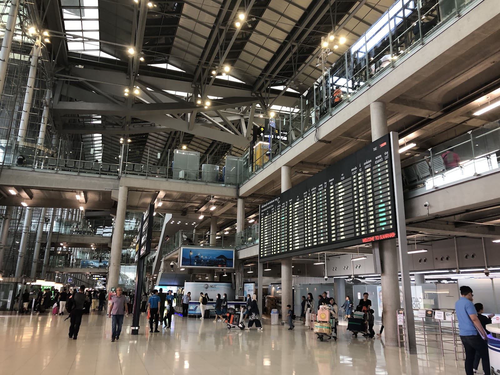 The arrivals hall at Suvarnabhumi Airport, with flight boards and passengers with luggage