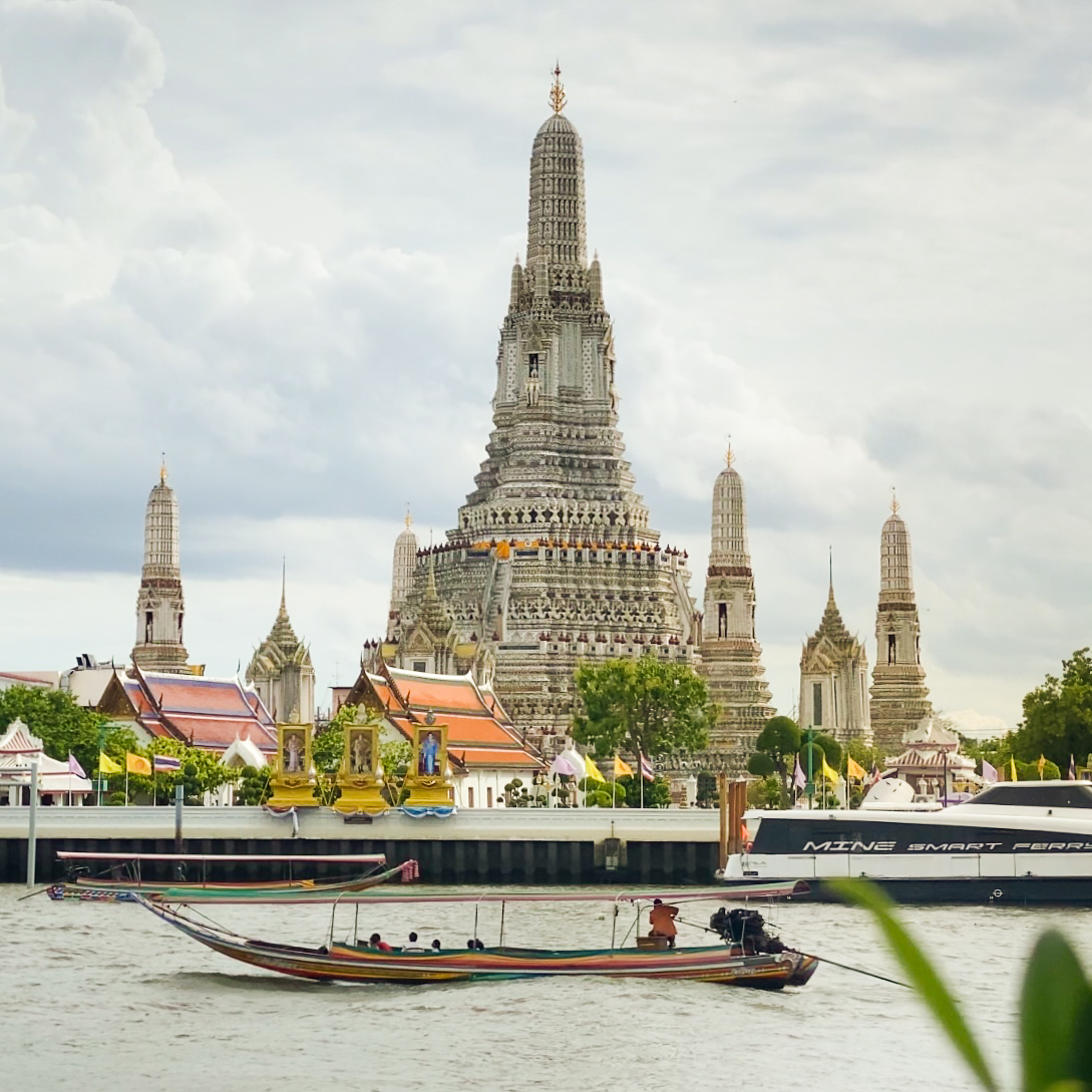 Wat Arun's central prang seen across the Chao Phraya River with a longtail boat