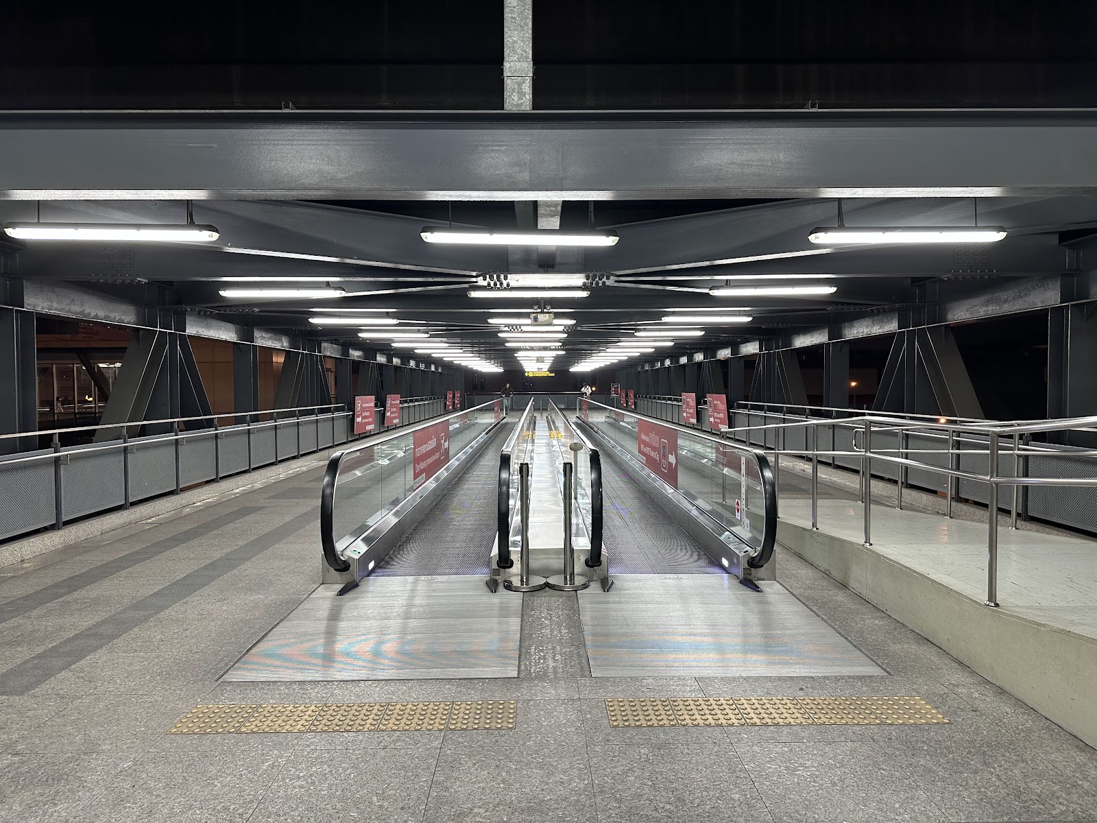 A long covered concourse with moving walkways at Don Mueang station