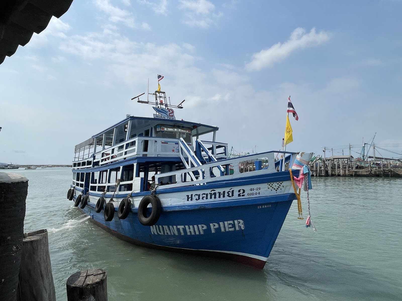 A blue-and-white passenger ferry moored at Nuanthip Pier in Ban Phe