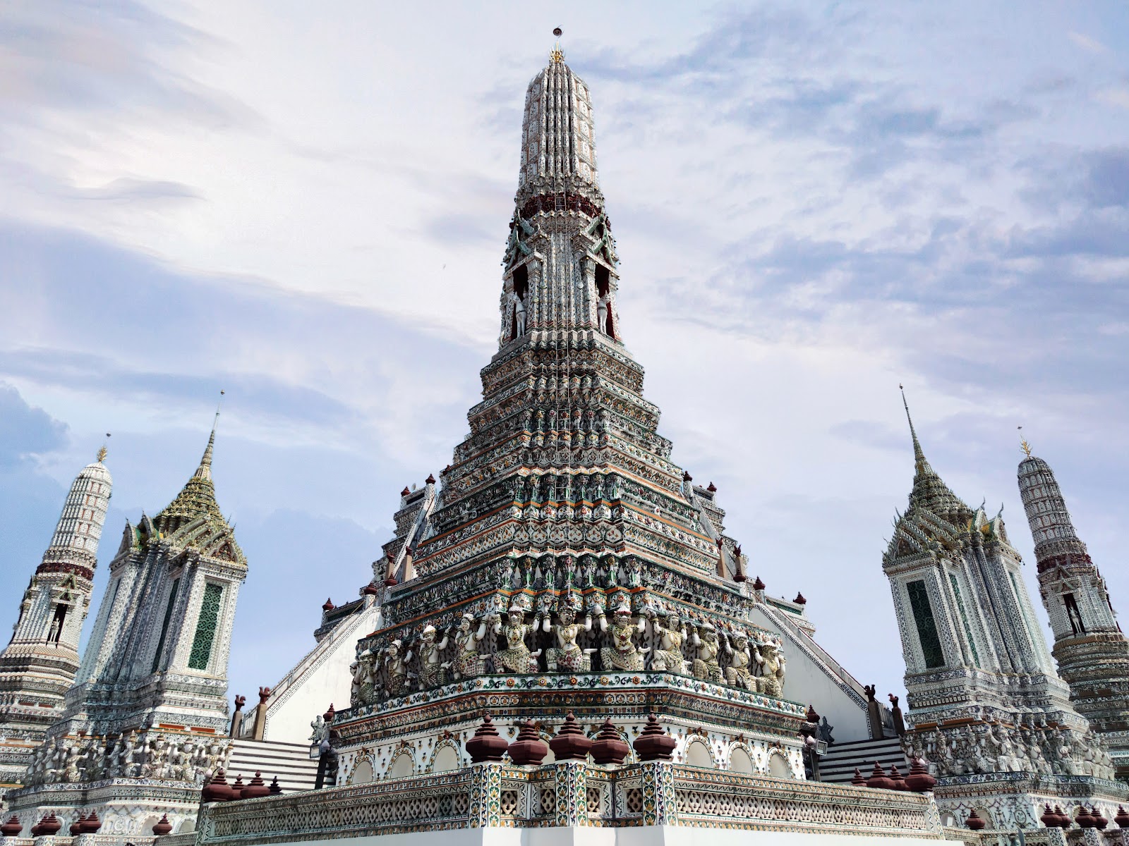 The central prang of Wat Arun with its smaller corner towers against a pale sky