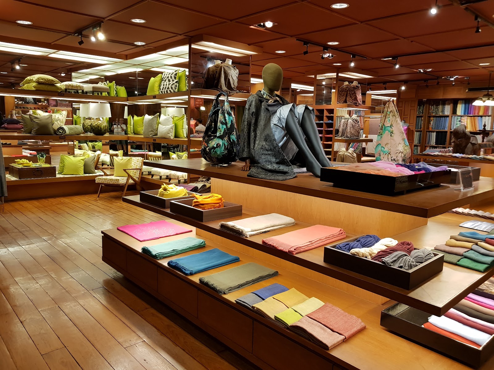 Folded silk scarves and fabrics on display tables inside the Jim Thompson Surawong flagship store