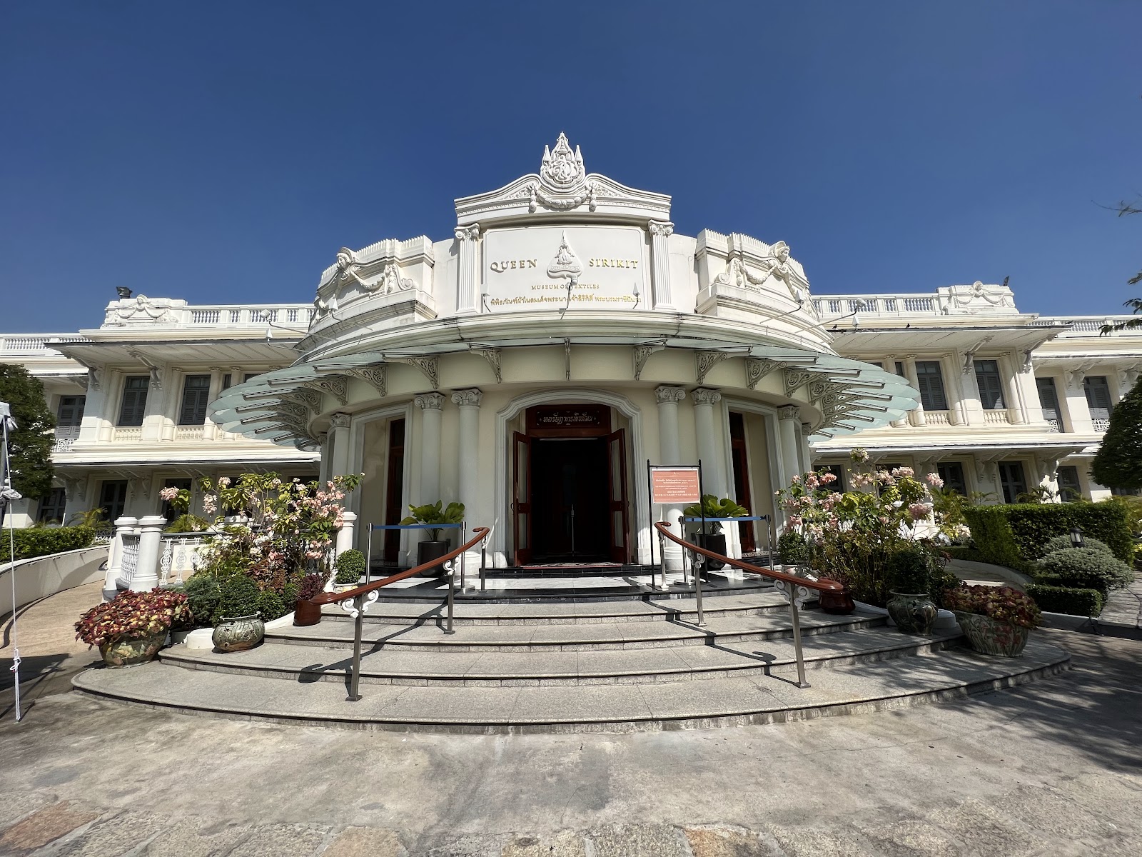 White facade of the Queen Sirikit Museum of Textiles in the Grand Palace grounds