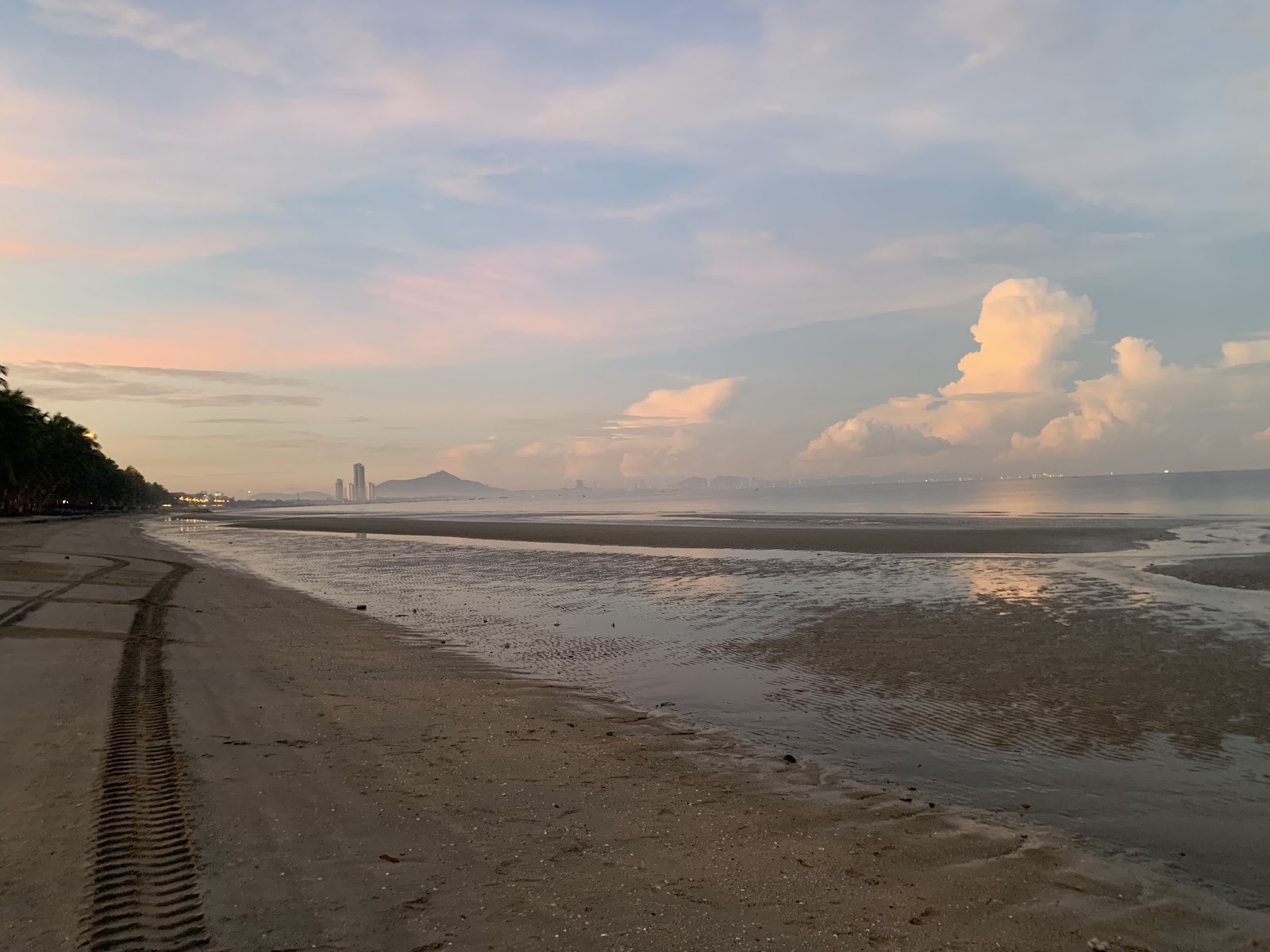 A wide, empty stretch of Bang Saen Beach at low tide under an evening sky