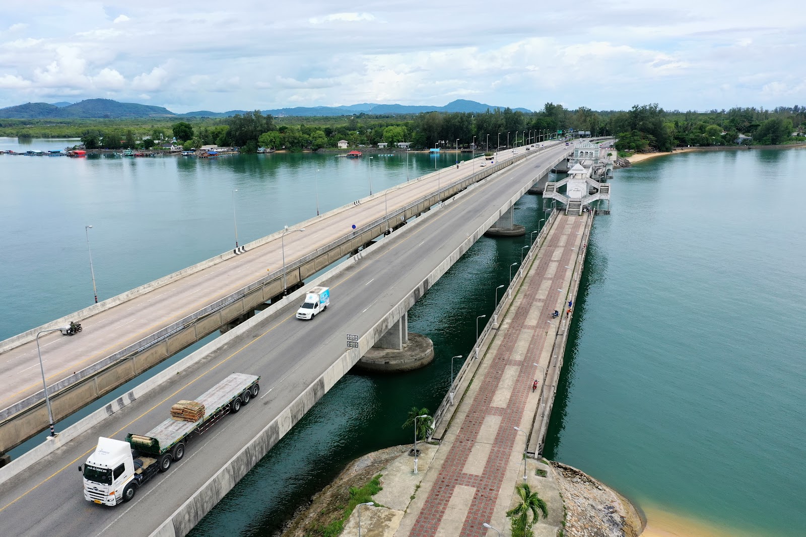 Trucks crossing the road bridges to Phuket Island over a turquoise channel, with the old Sarasin Bridge alongside