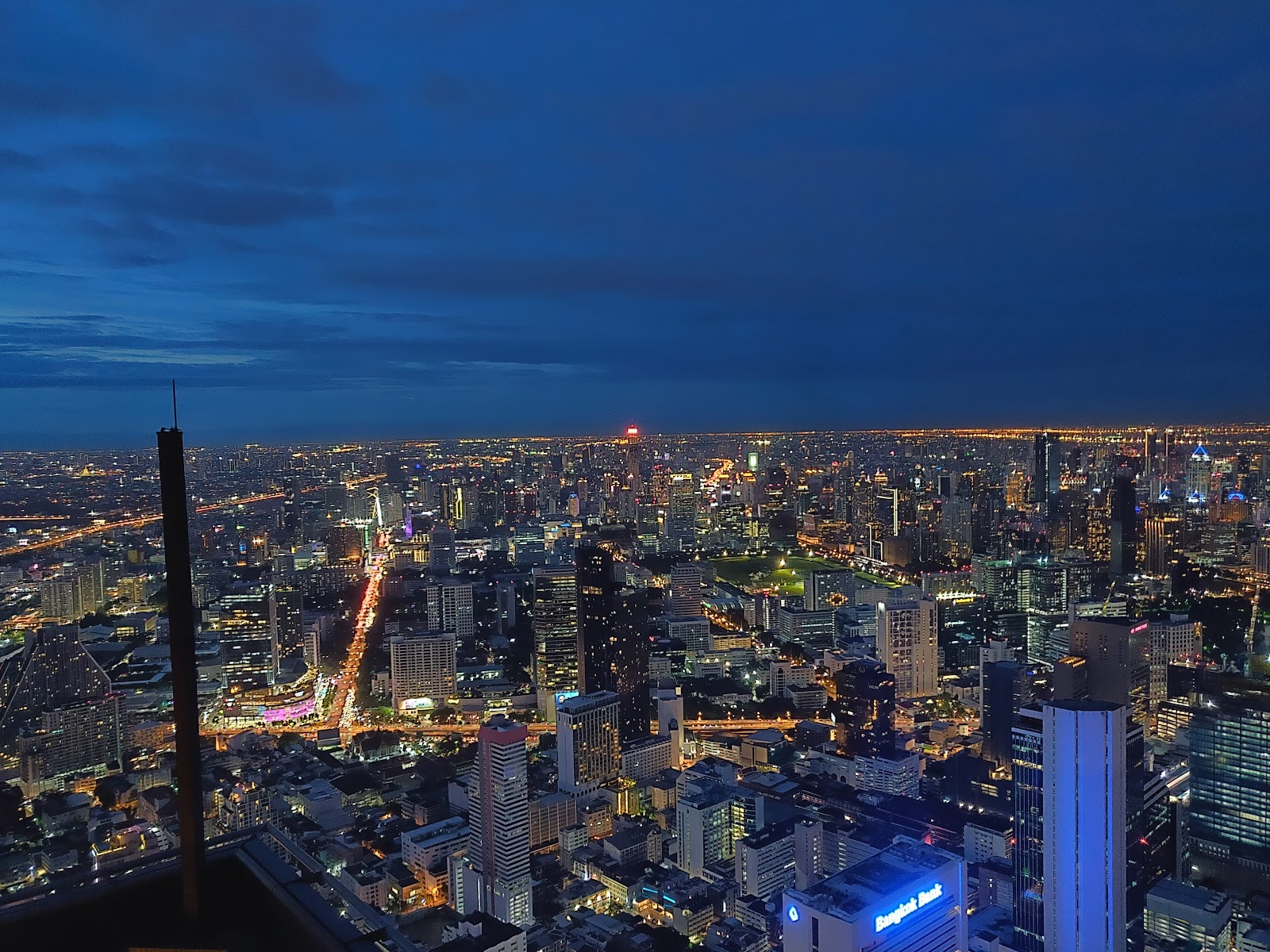 Bangkok's lit streets and towers stretching to the horizon at dusk, seen from the SkyWalk