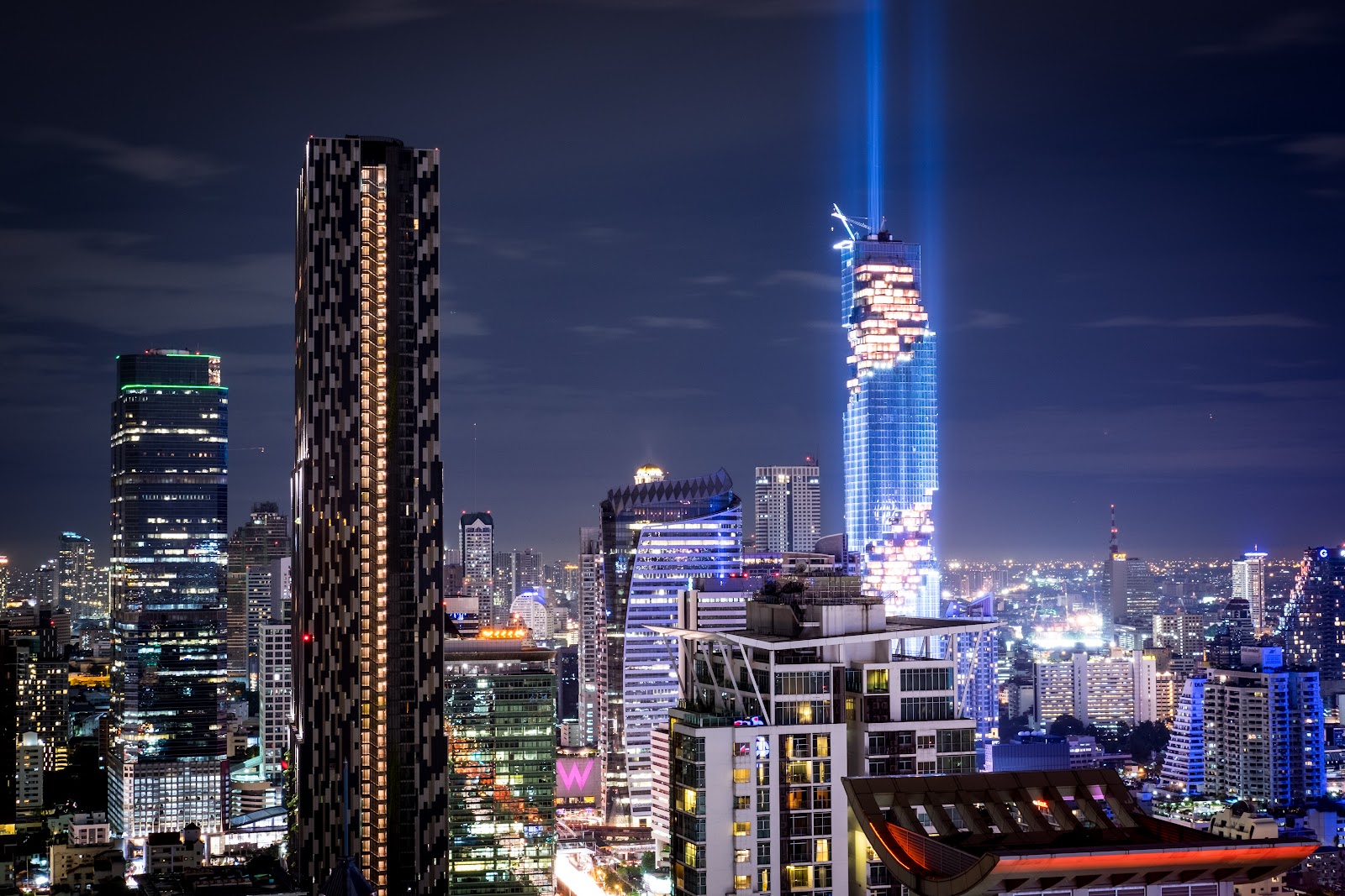 The King Power Mahanakhon tower lit at night among apartment and office towers
