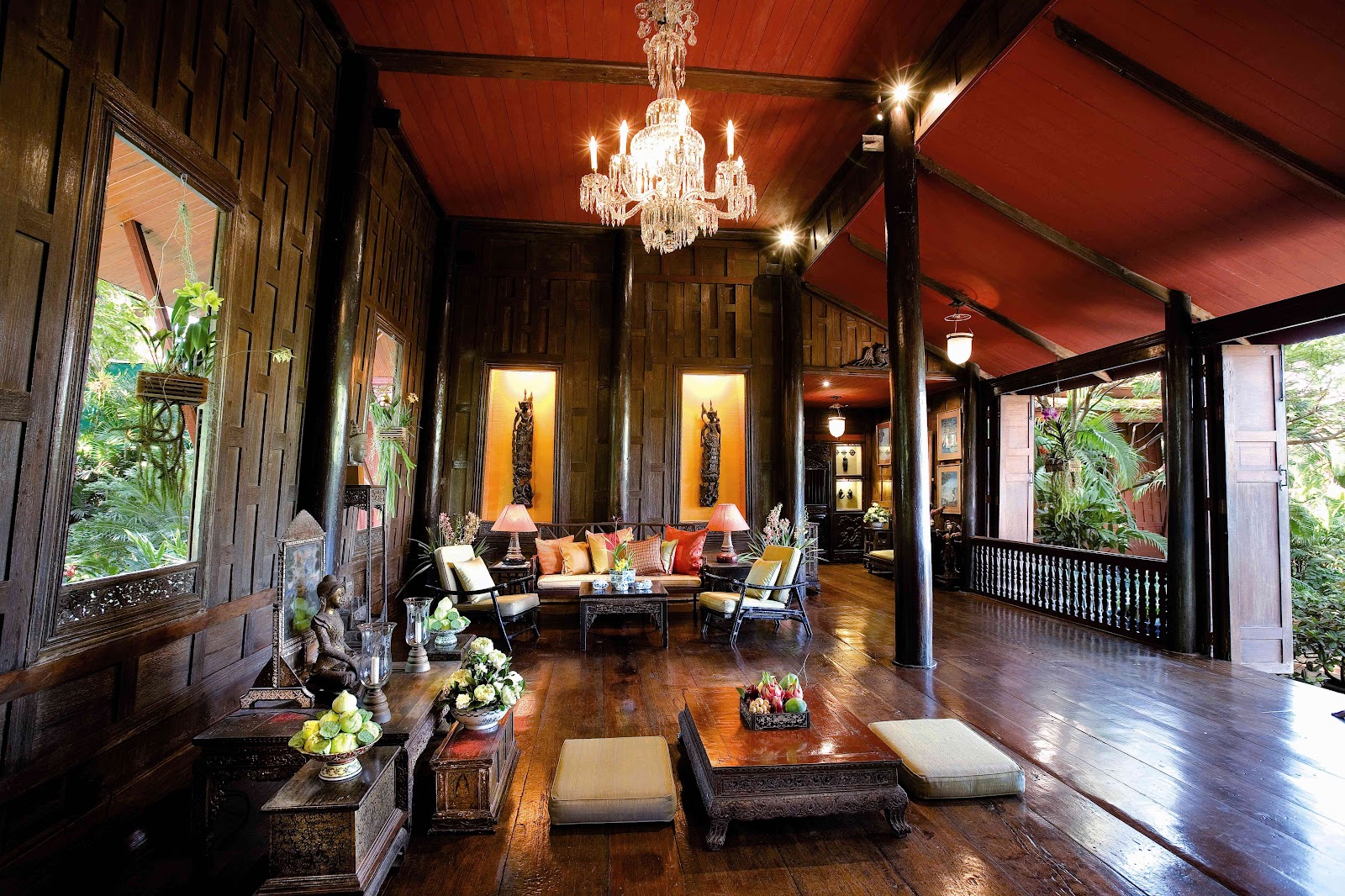 The wood-paneled living room of Jim Thompson House with antique furniture and a chandelier