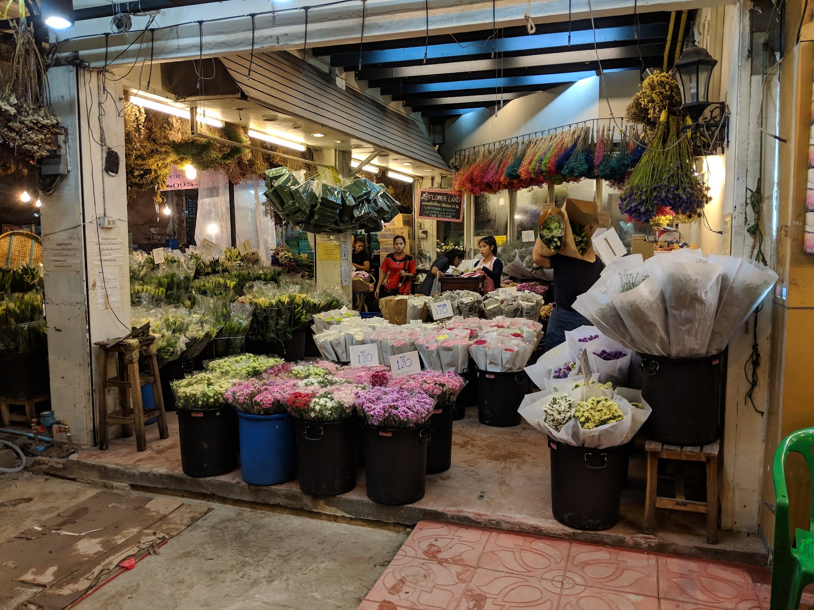 Buckets of roses and bundled cut flowers in front of a flower shop at Pak Khlong Talat
