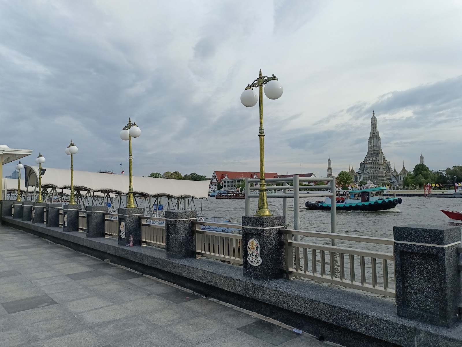 The riverside promenade at Tha Tien pier with the prang of Wat Arun across the Chao Phraya