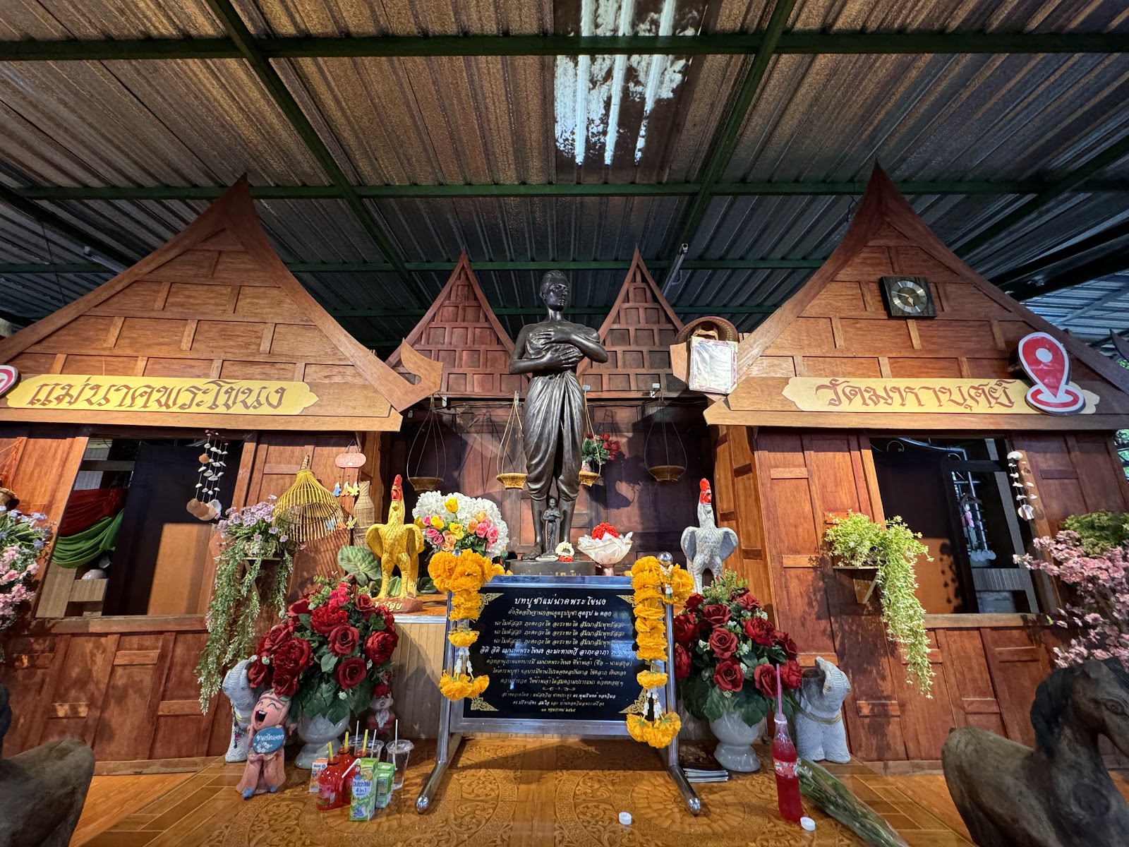 The Mae Nak shrine at Wat Mahabut, with a statue of Mae Nak among wooden Thai-style houses and flower offerings