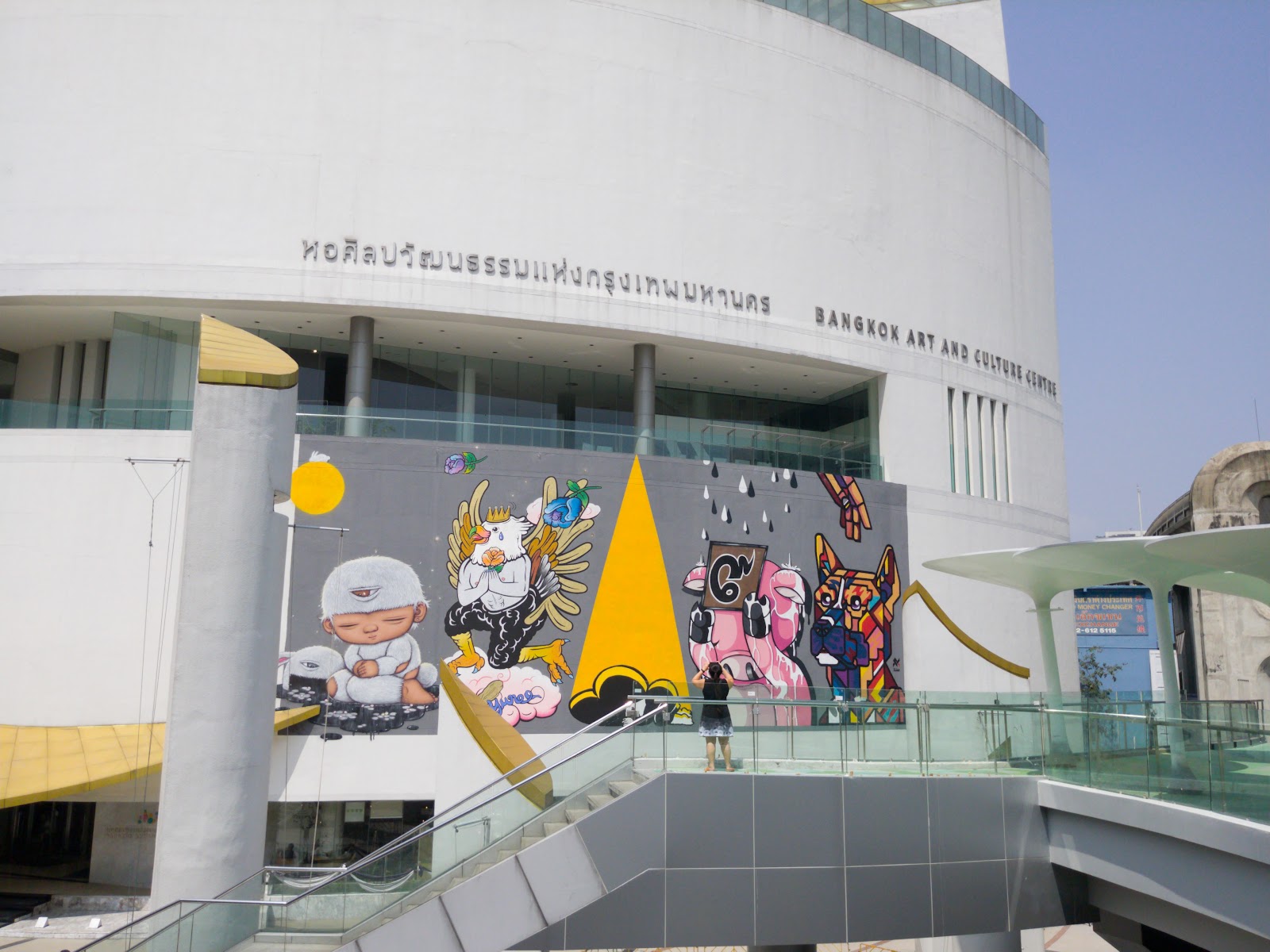 The curved white facade of the Bangkok Art and Culture Centre with a large mural