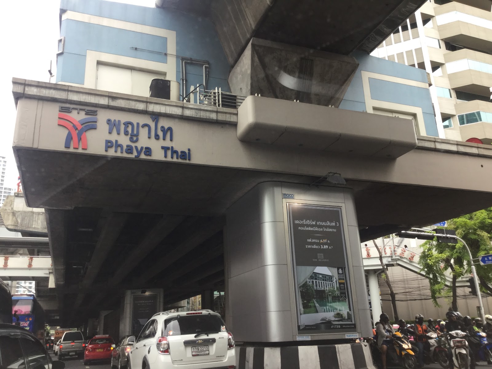 The Phaya Thai station sign on the elevated rail structure above the road