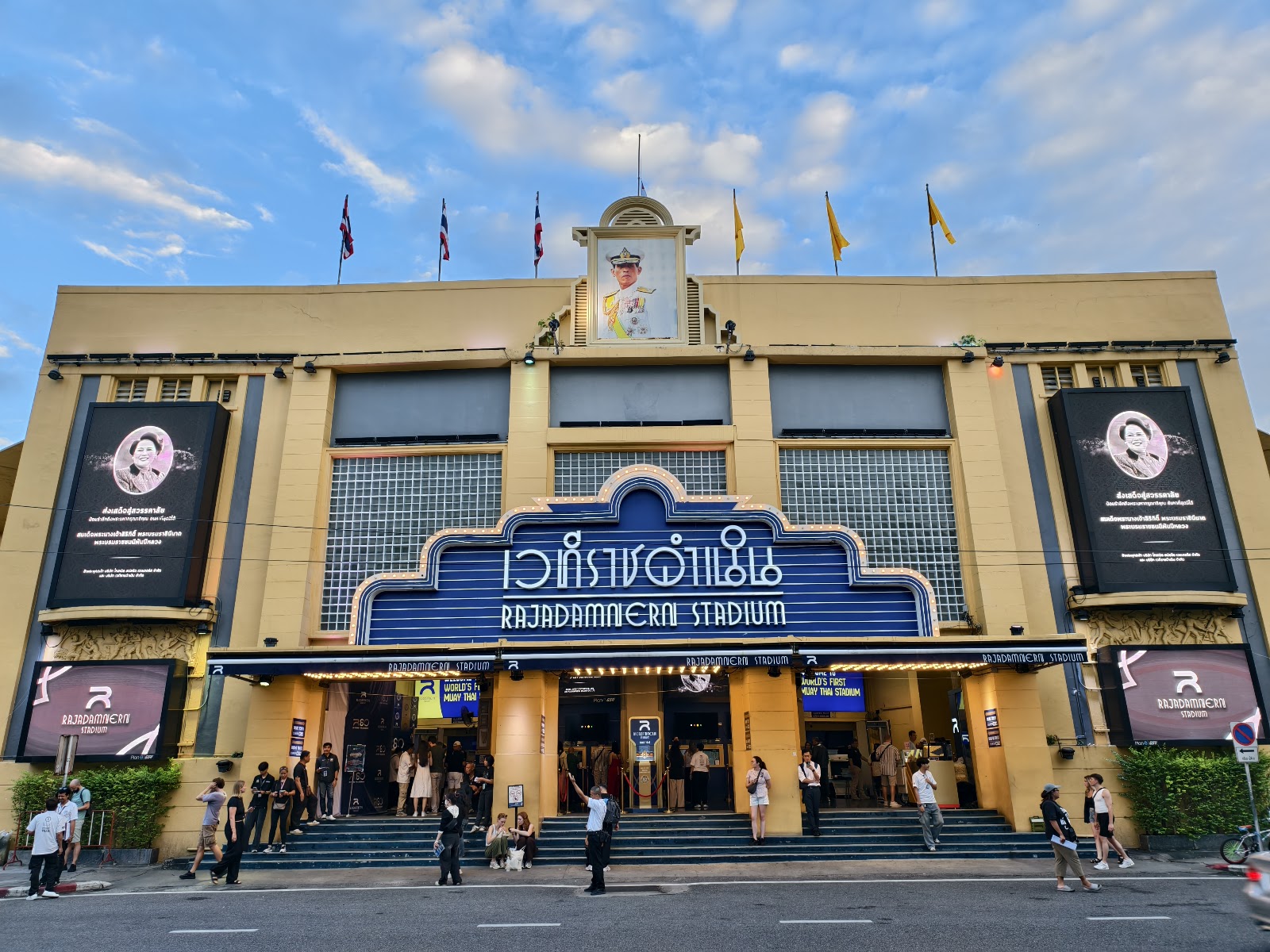 The cream-colored facade and main entrance of Rajadamnern Stadium under a blue sky