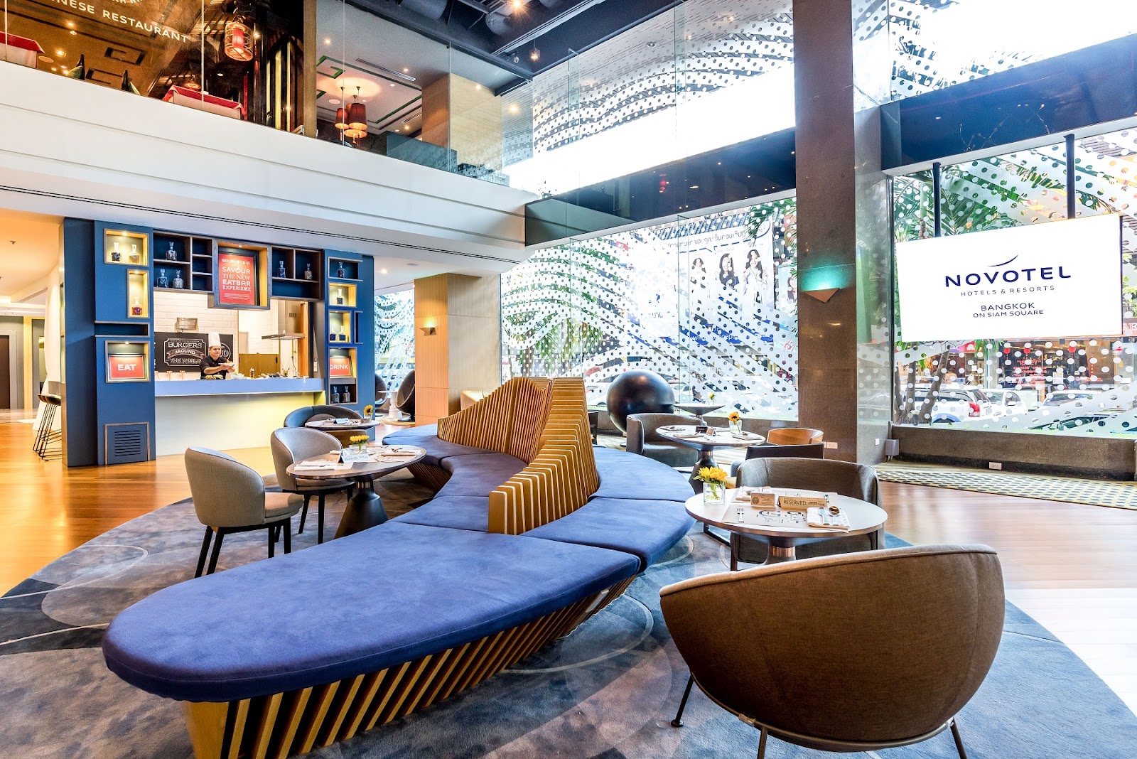 Lobby lounge of Novotel Bangkok on Siam Square with blue sofas and the Novotel sign