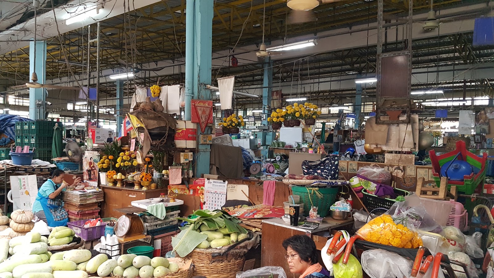 Stalls of marigolds, flowers and produce inside a covered market hall at Pak Khlong Talat