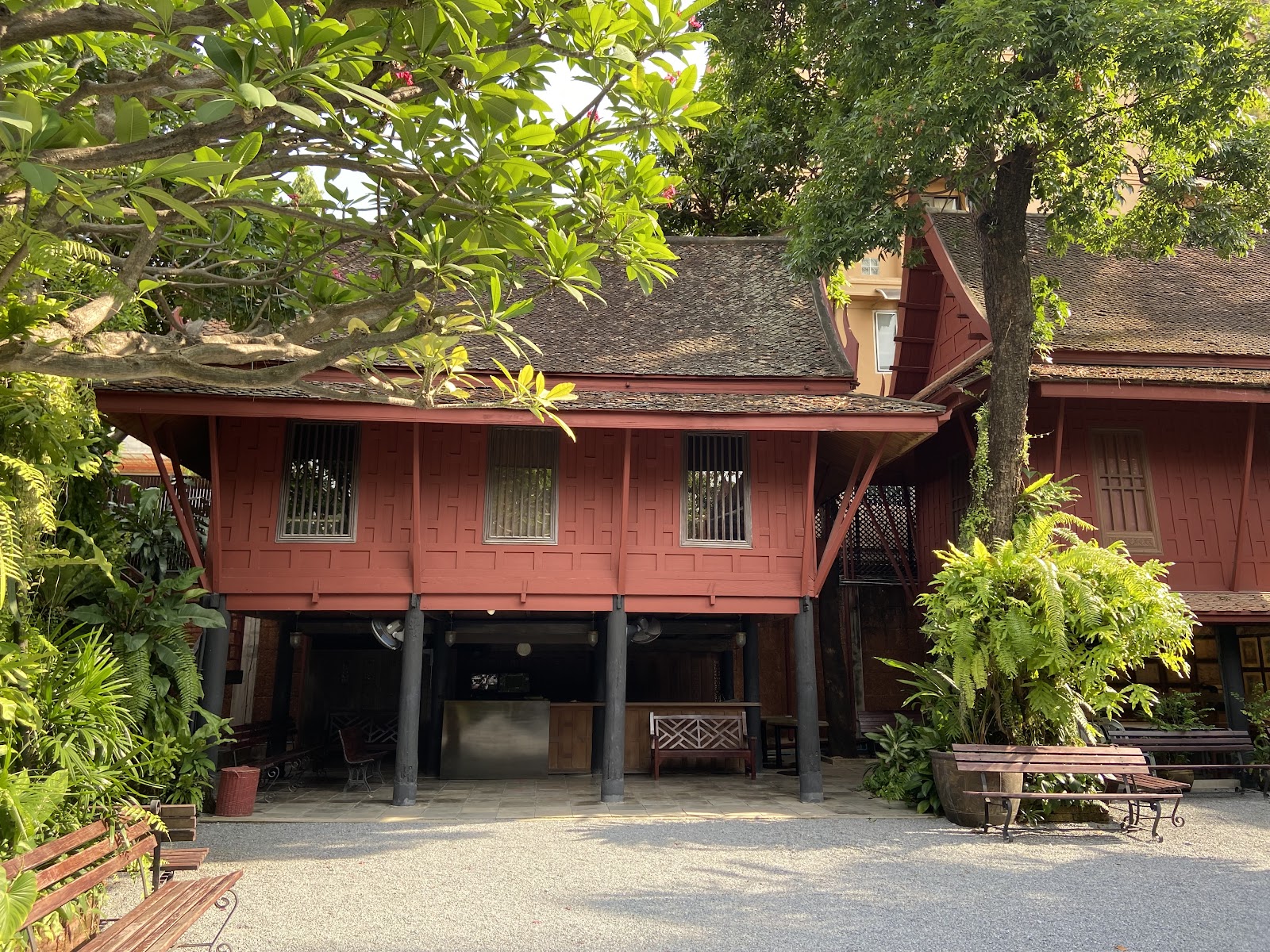 The red teak houses of the Jim Thompson House Museum raised on pillars among trees