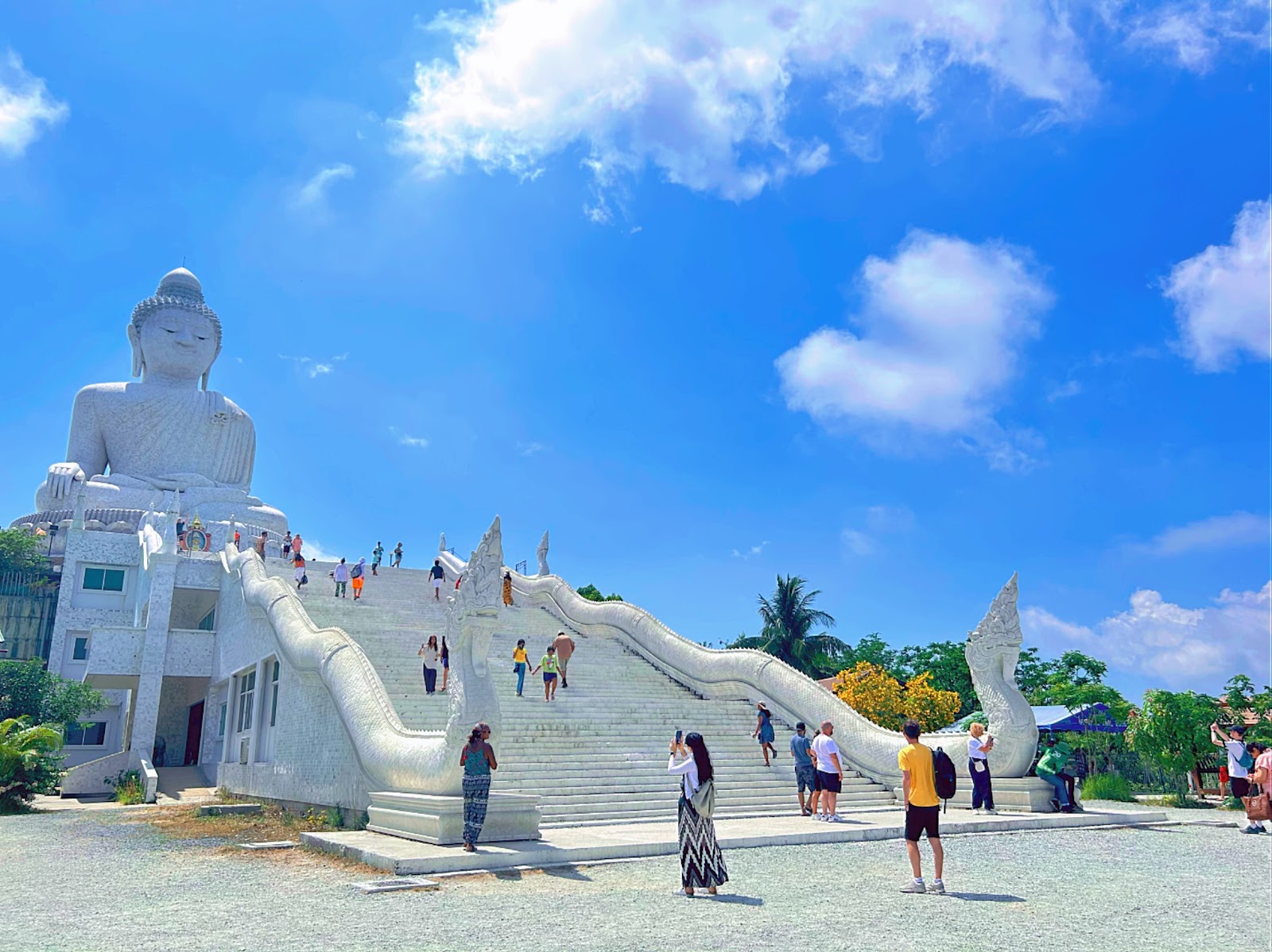 The white marble Big Buddha statue at the top of a broad staircase under a blue sky
