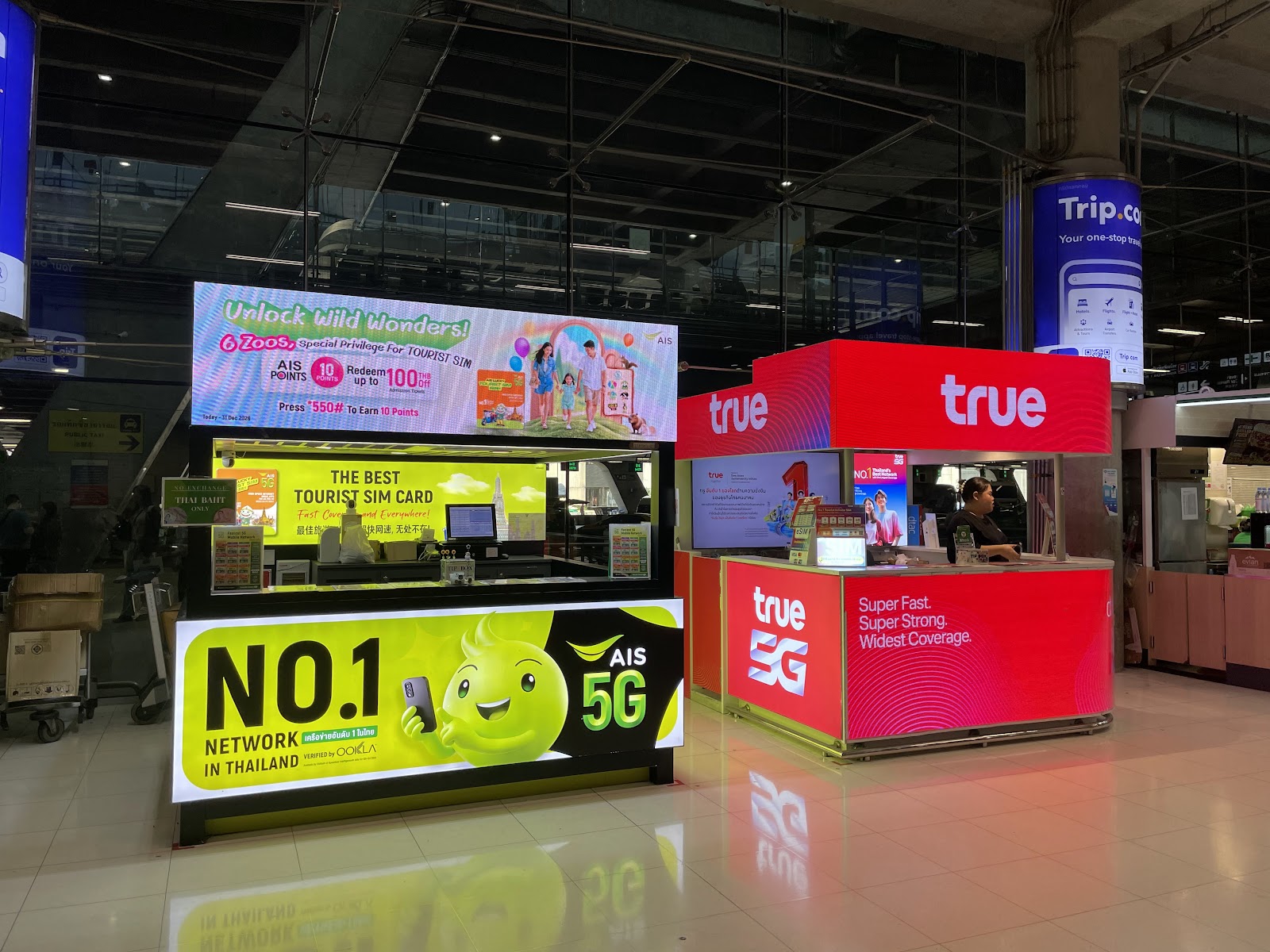 Side-by-side AIS and True mobile network counters selling tourist SIM cards in the Suvarnabhumi arrivals hall