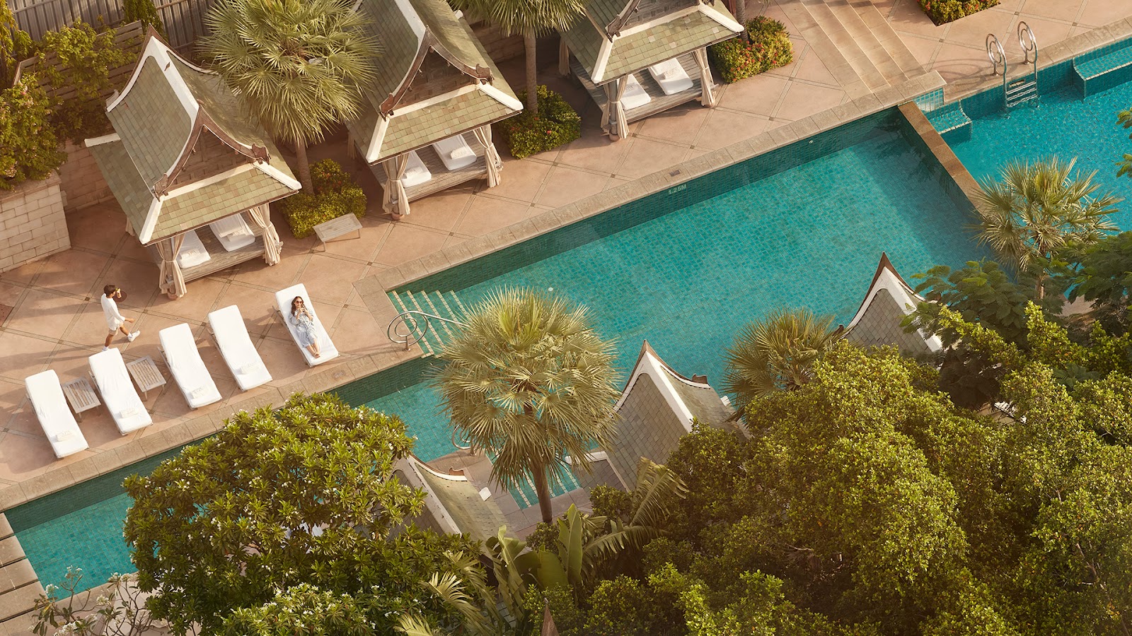 The tiered pool at The Peninsula Bangkok lined with Thai-style salas and palms