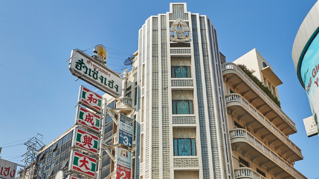 A white Chinatown building with Hua Seng Heng’s tall vertical sign against a blue sky