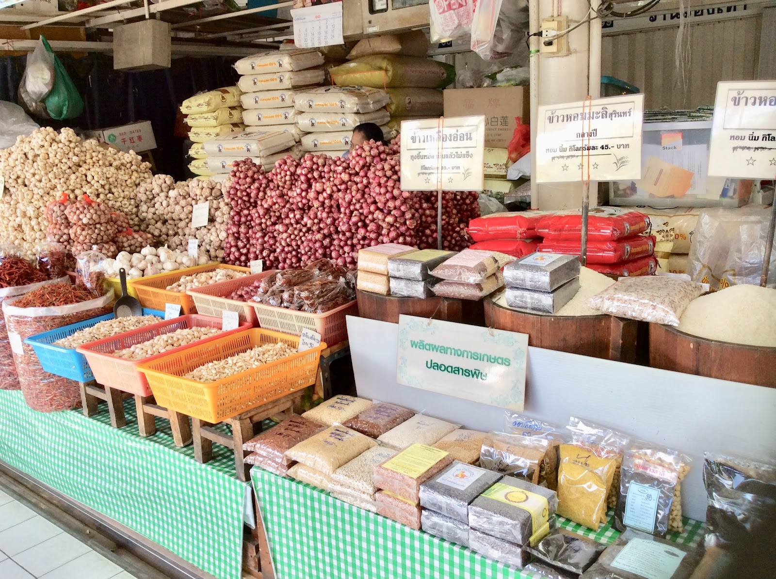 Bins of dried chilies, garlic, shallots and packaged dry goods at a stall in Or Tor Kor Market