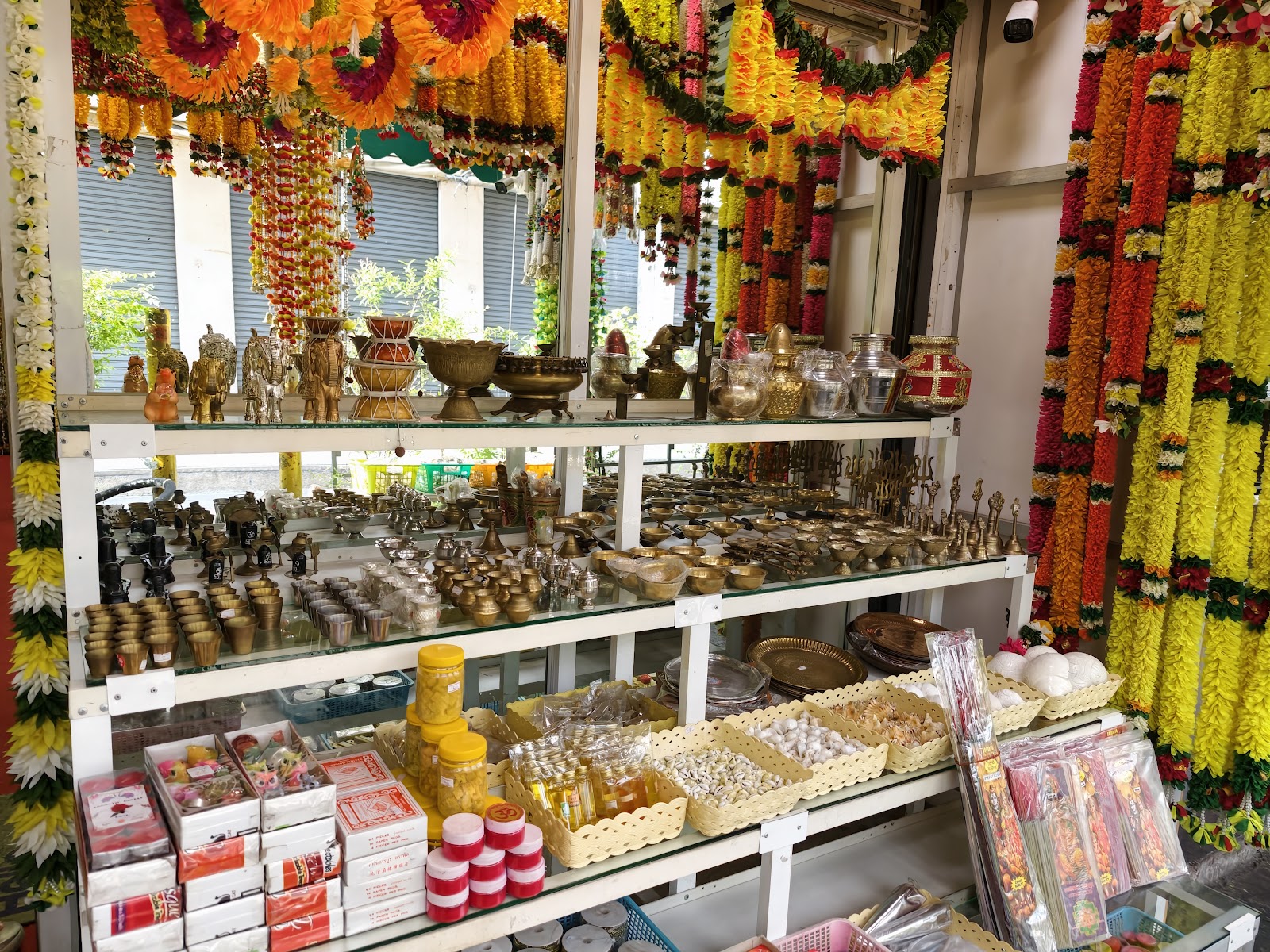 A shop in Phahurat hung with marigold garlands and shelves of brass religious goods