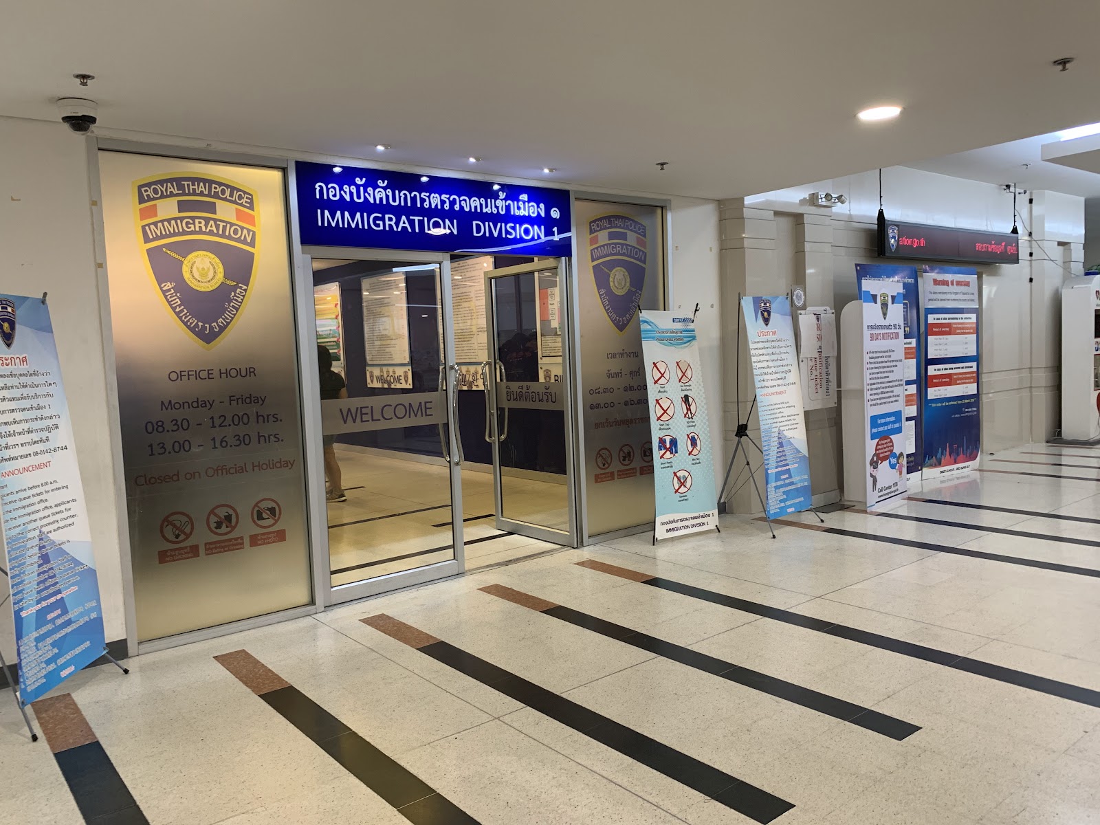 Glass entrance doors under an Immigration Division 1 sign inside Building B