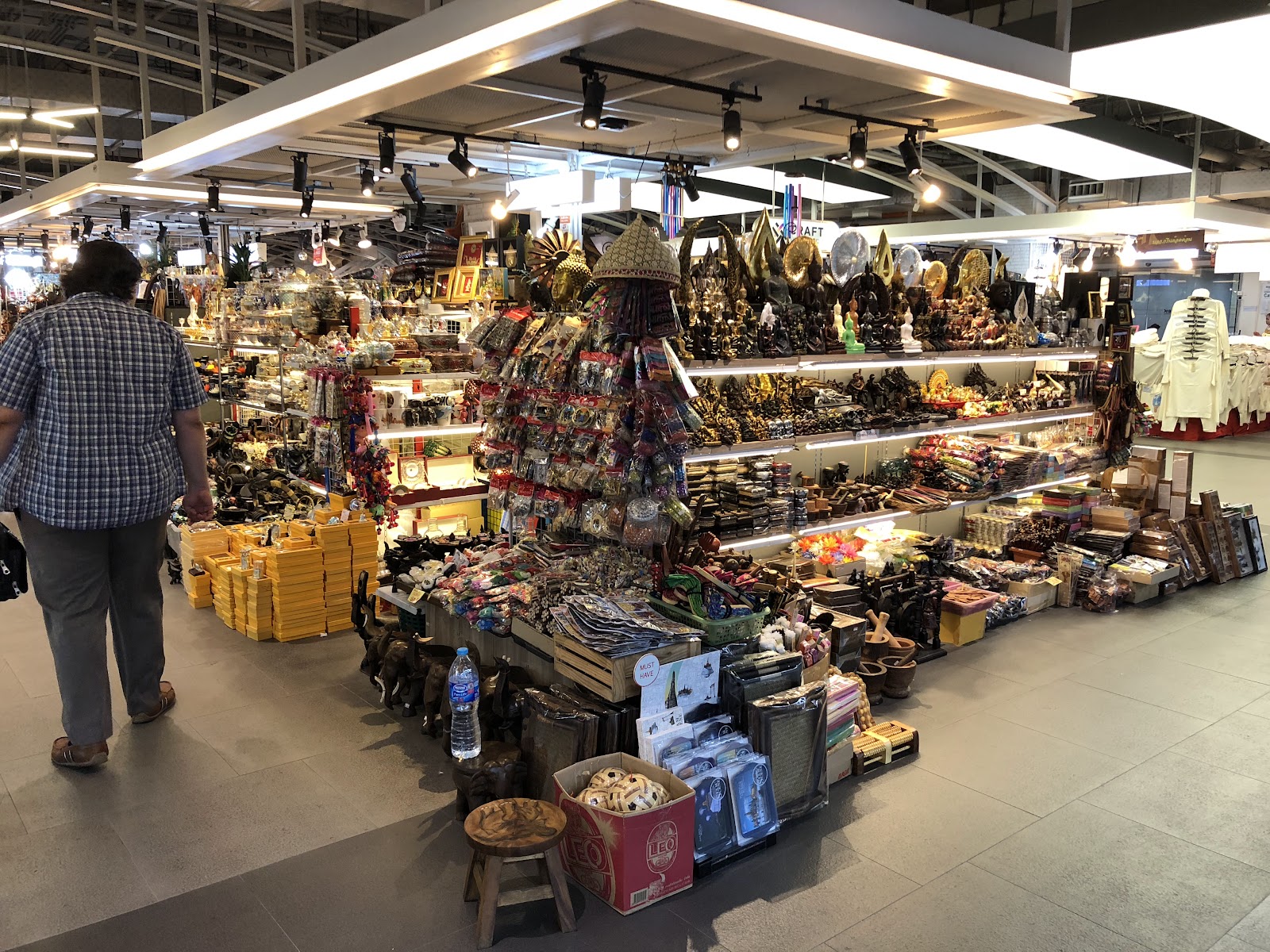 A souvenir stall inside MBK Center crowded with bags, carvings and handicrafts