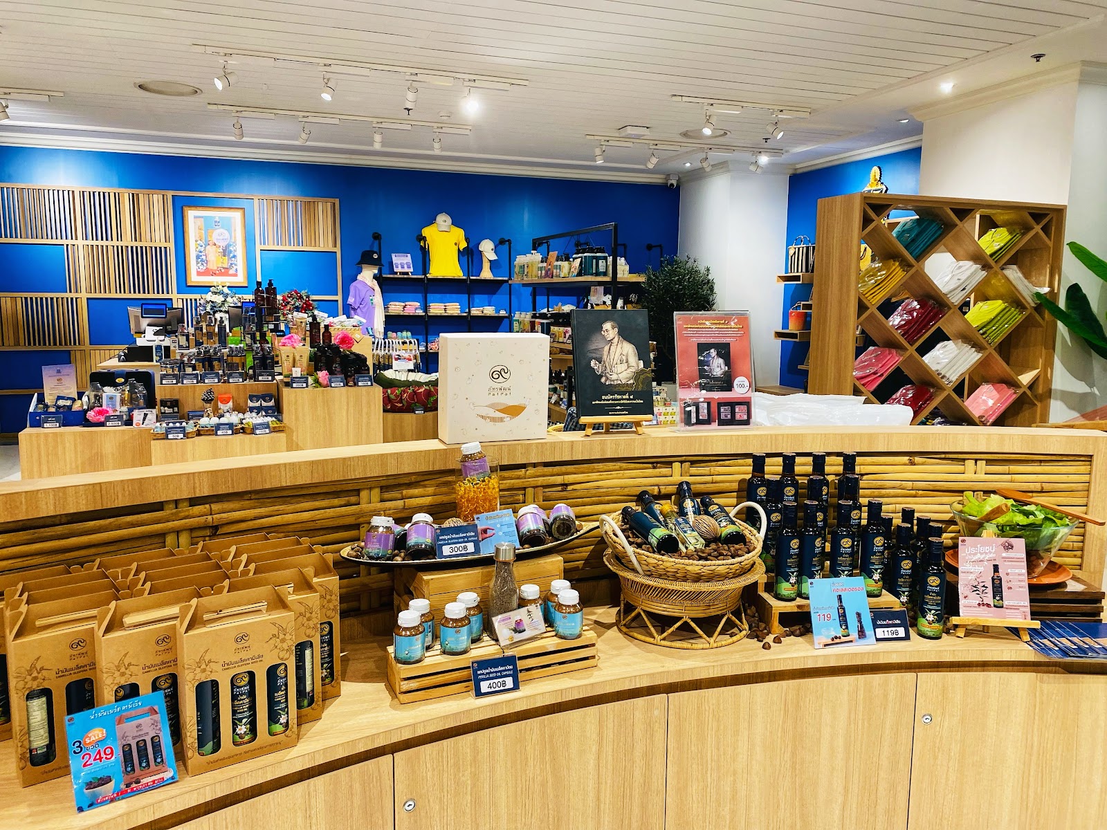 A shop inside ICONSIAM displaying Thai-made gifts, textiles and packaged products on wooden shelves