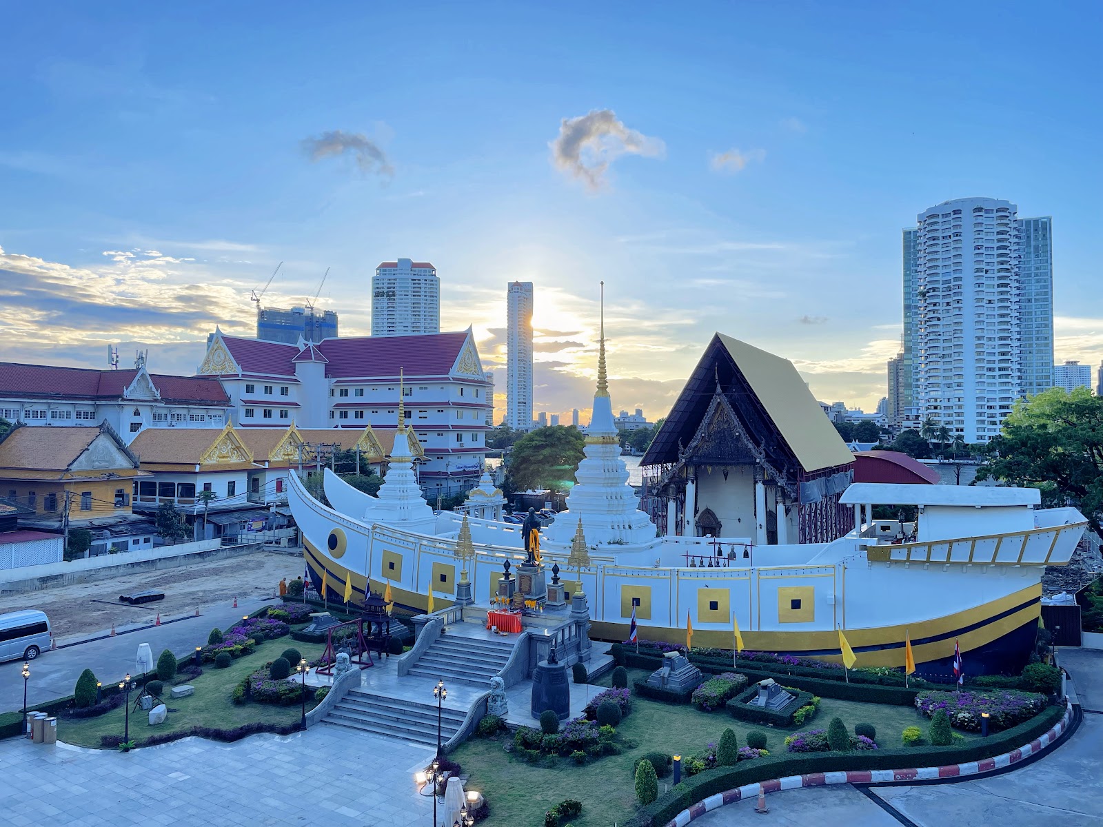 The white and gold ship-shaped chedi of Wat Yan Nawa with its spire, seen from above with Sathorn towers behind