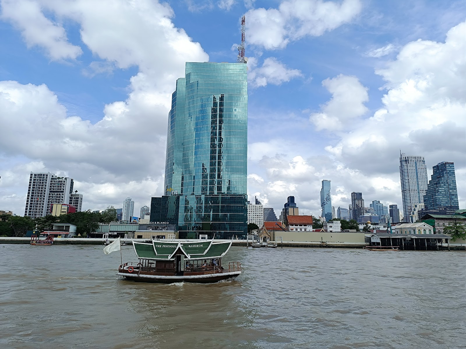 A Chao Phraya river ferry crossing in front of the Bangkok skyline near Sathorn