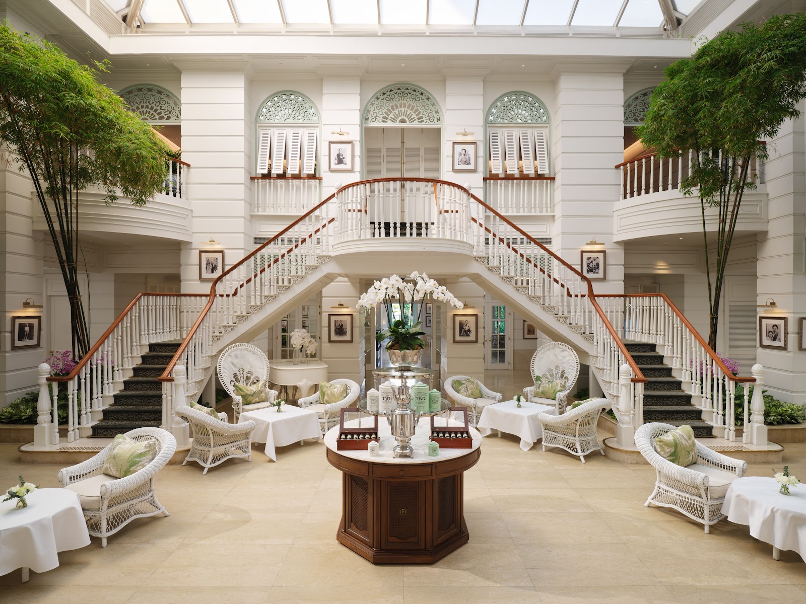 The Authors' Lounge with white wicker chairs beneath a double staircase and glass roof