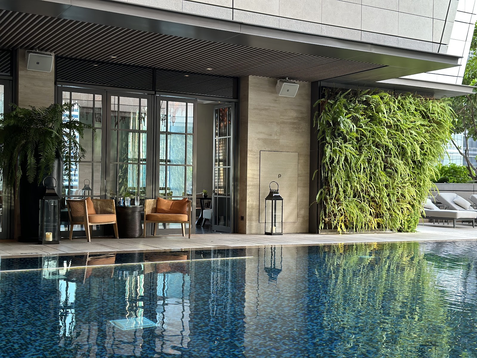 Rosewood Bangkok's ninth-floor pool with a green wall and lounge chairs under the tower