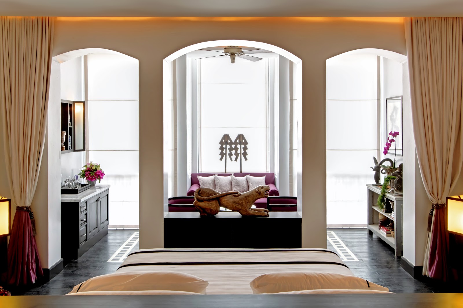 A suite bedroom with arched windows, a daybed and Thai decorative details