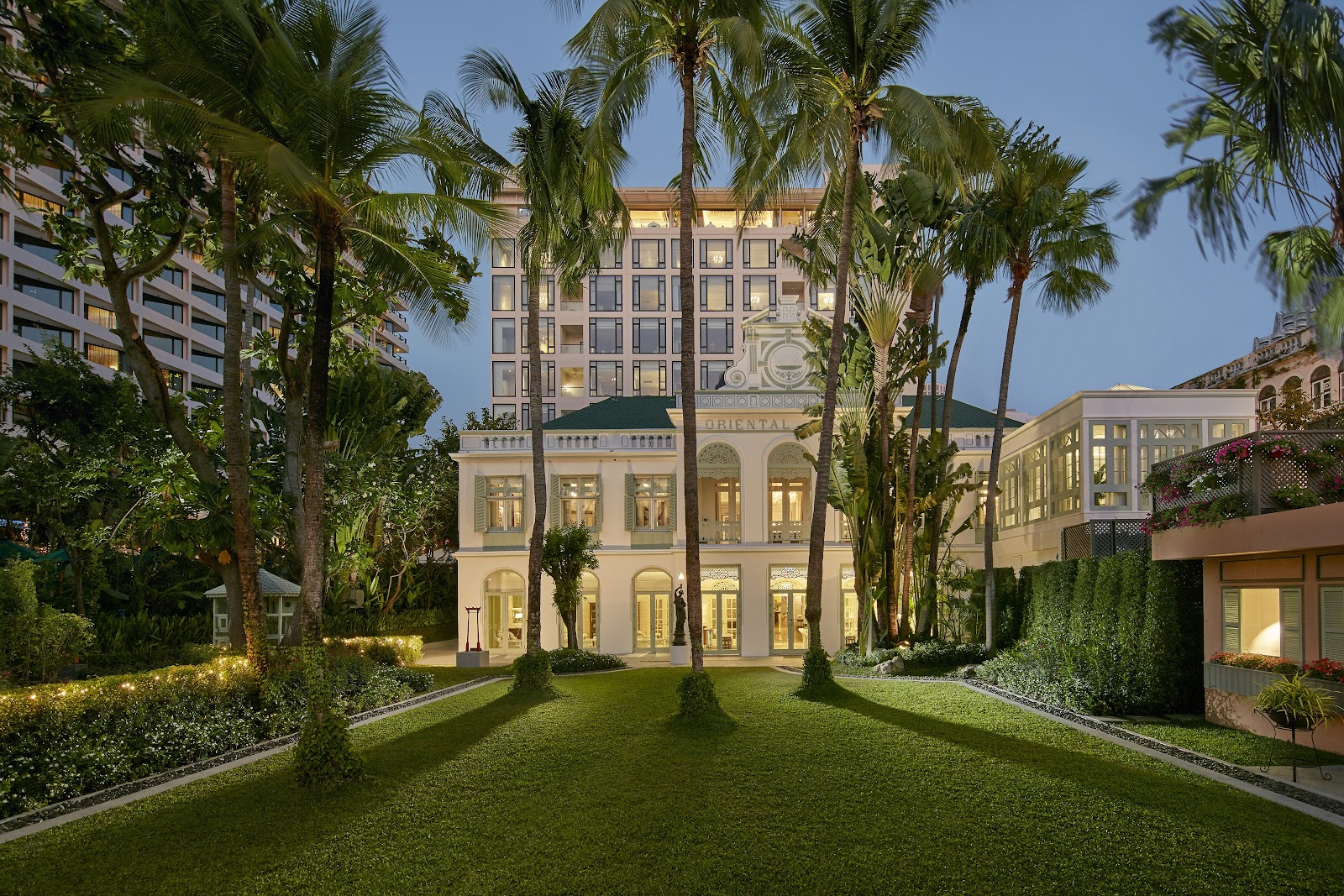 The Authors' Wing of Mandarin Oriental, Bangkok behind its palm-lined lawn at dusk