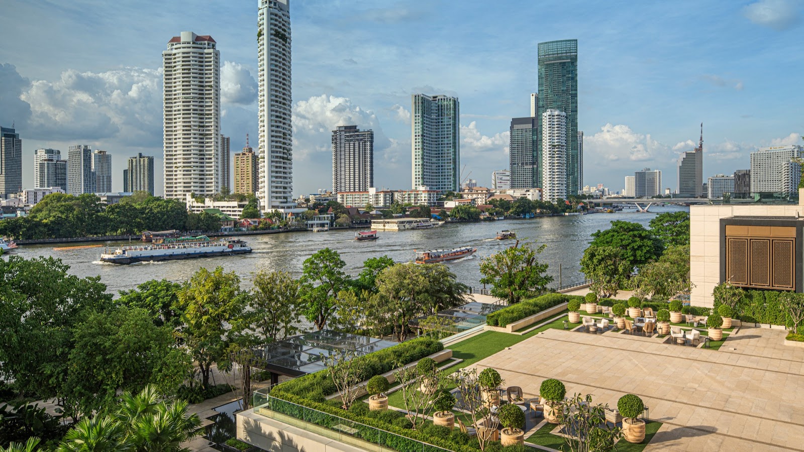 Four Seasons Hotel Bangkok's riverside gardens with the Chao Phraya and skyline behind