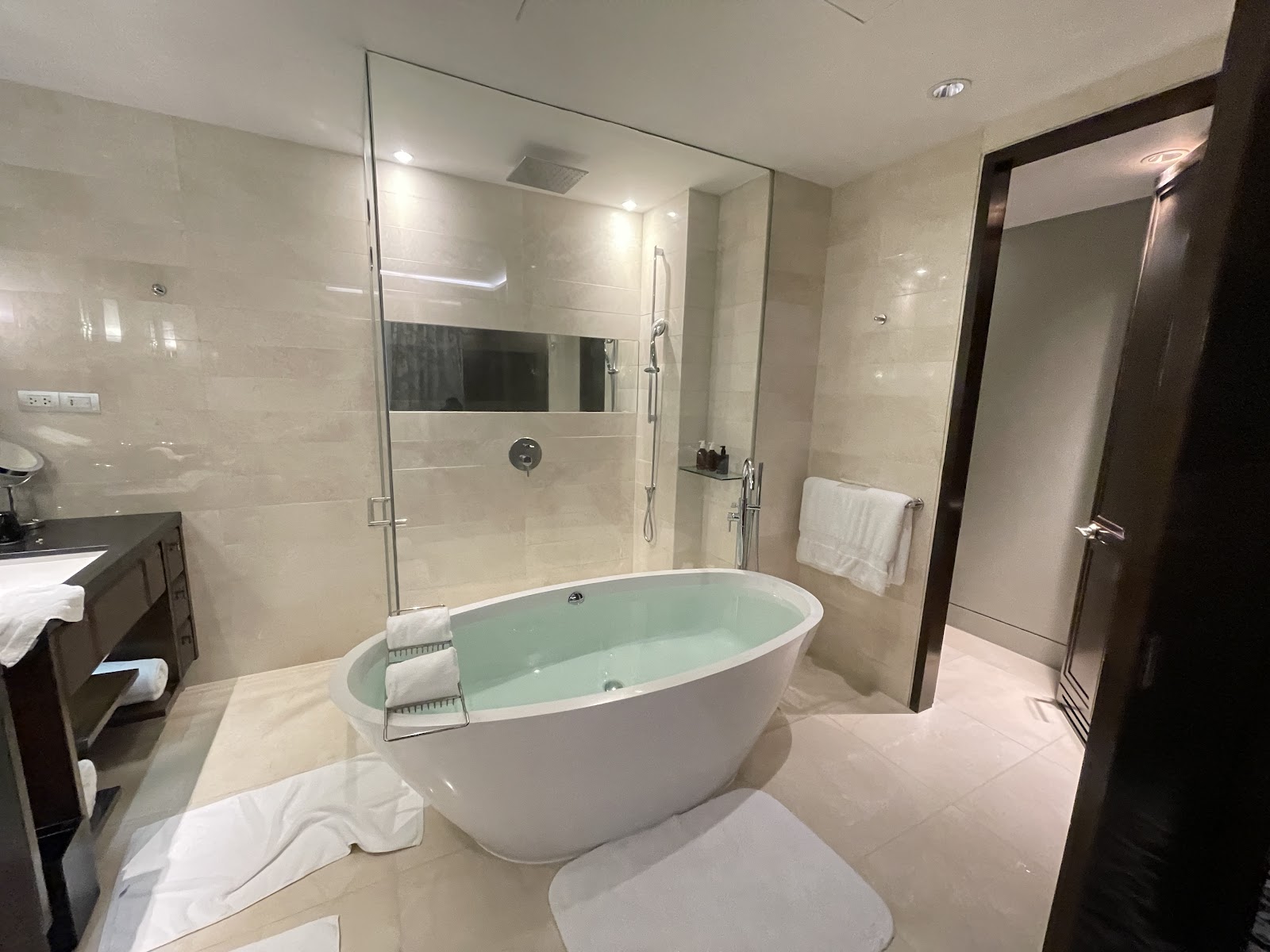 A marble bathroom with a freestanding soaking tub and a glass-walled rain shower