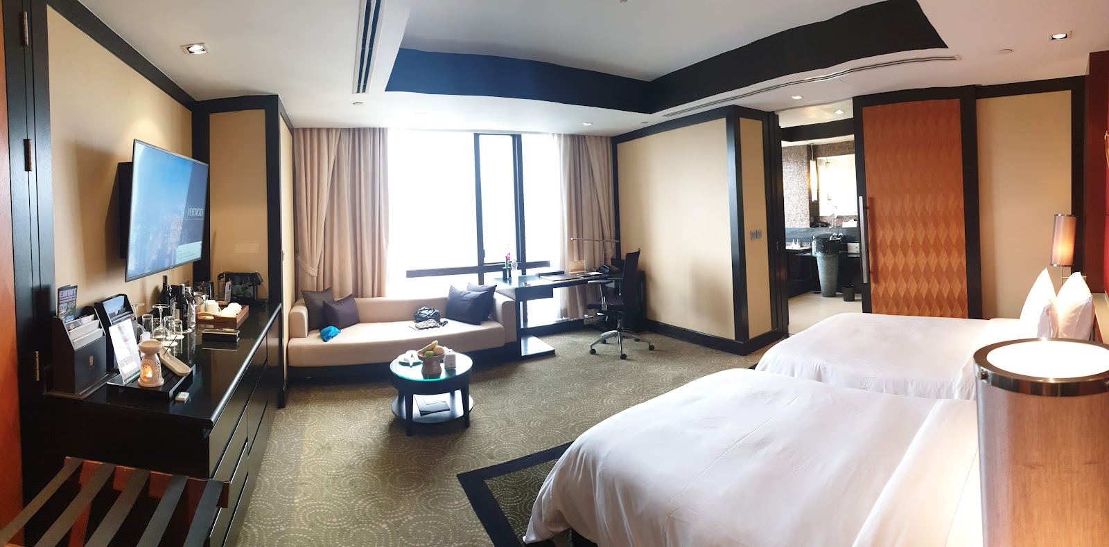 A Banyan Tree Bangkok guest room with twin beds, a sofa and floor-to-ceiling windows