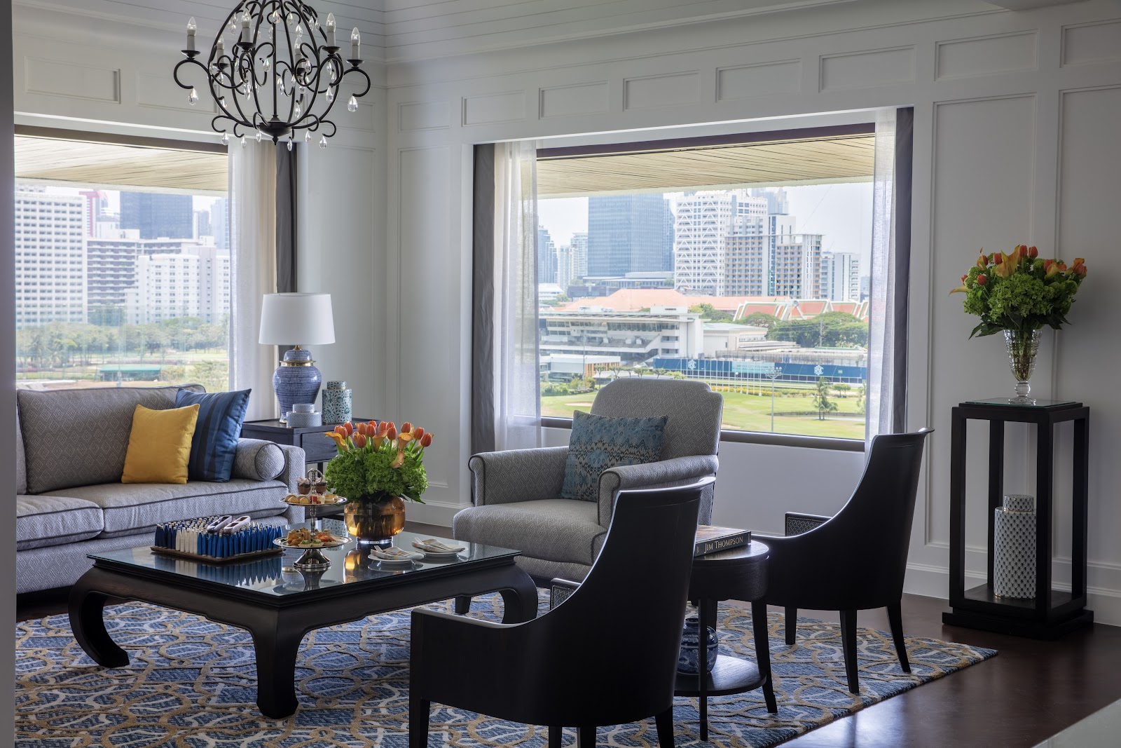 An Anantara Siam suite living room with a window over the Royal Bangkok Sports Club