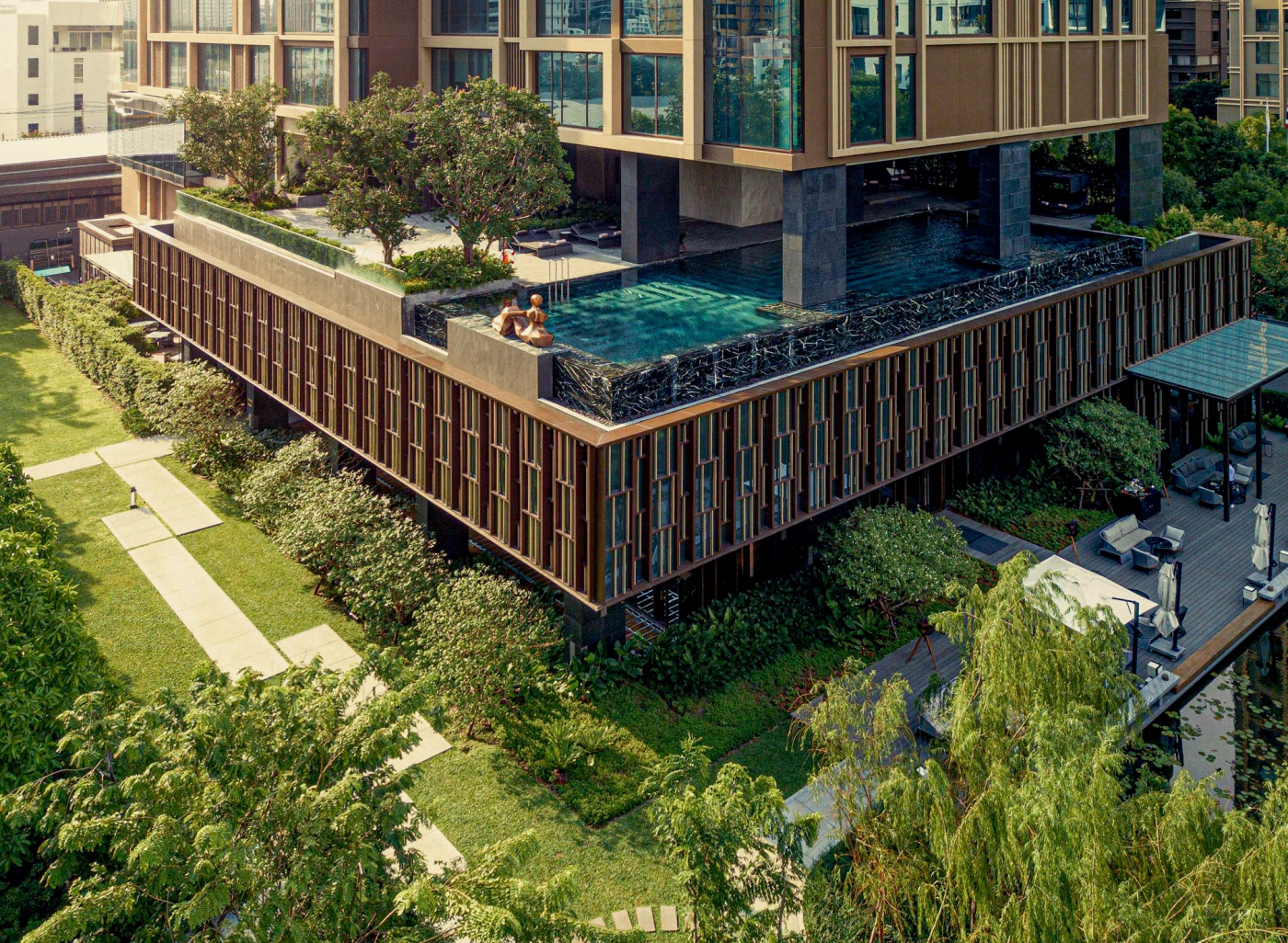Kimpton Maa-Lai Bangkok's garden-level infinity pool framed by planting and the hotel tower