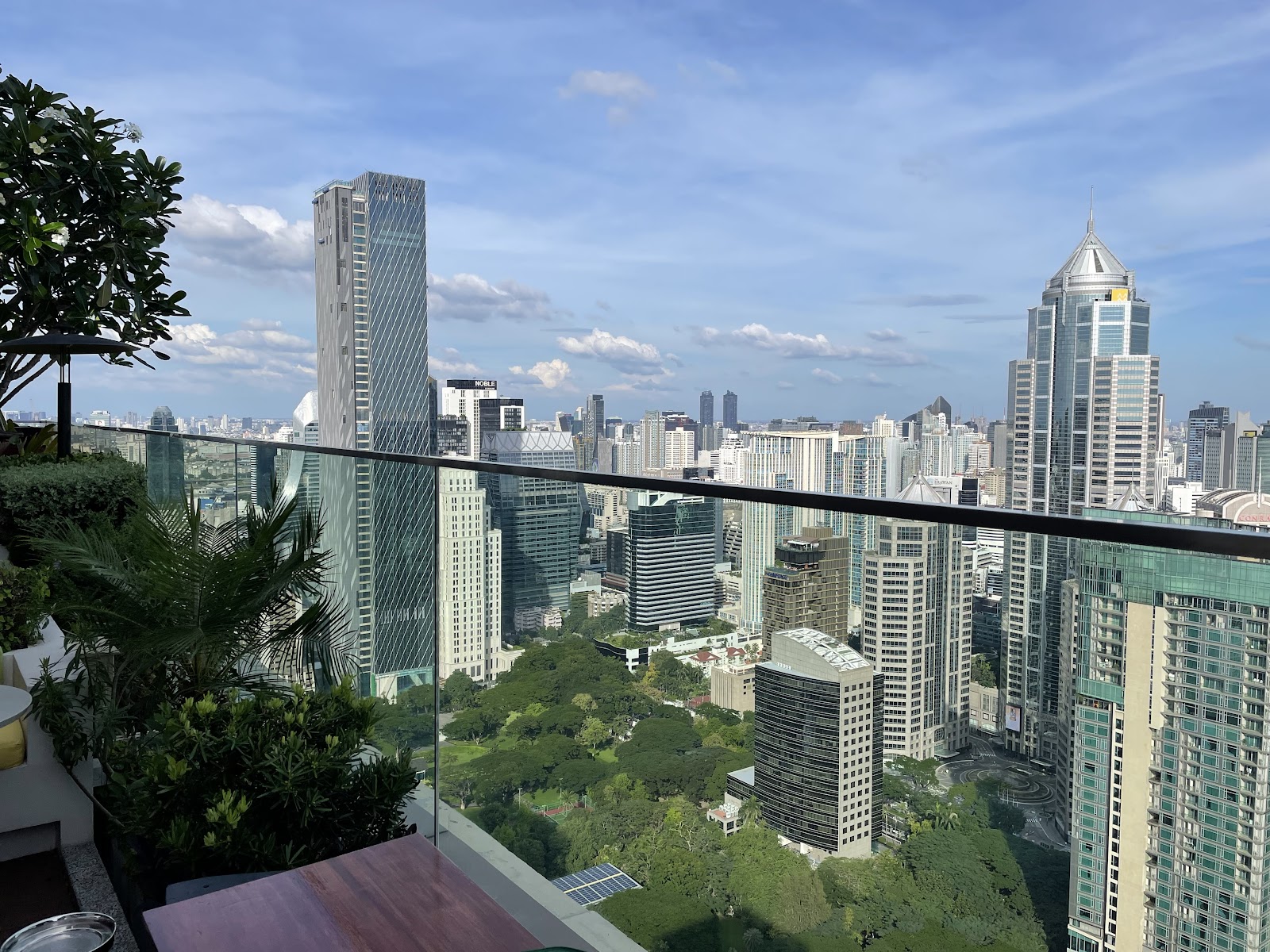 View from a high balcony over green treetops and Bangkok towers
