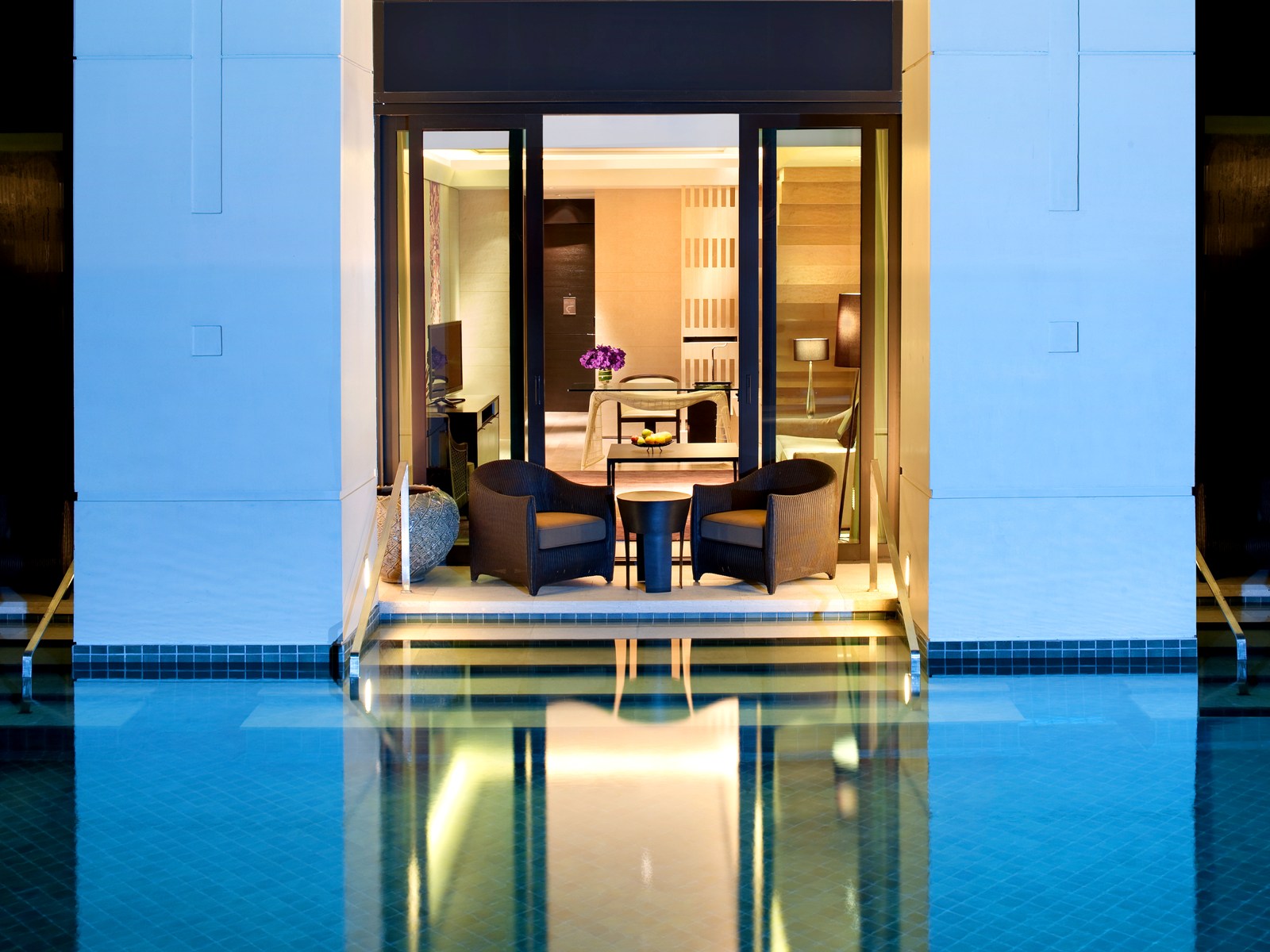 A lit Cabana room terrace opening directly onto a pool at dusk