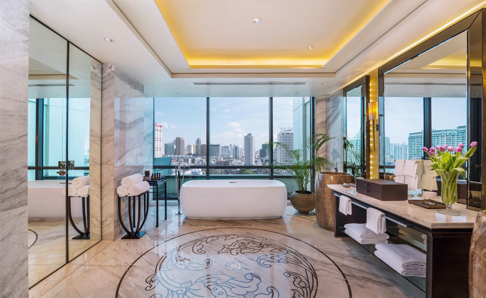 Marble bathroom with a freestanding bathtub beside floor-to-ceiling windows over the city